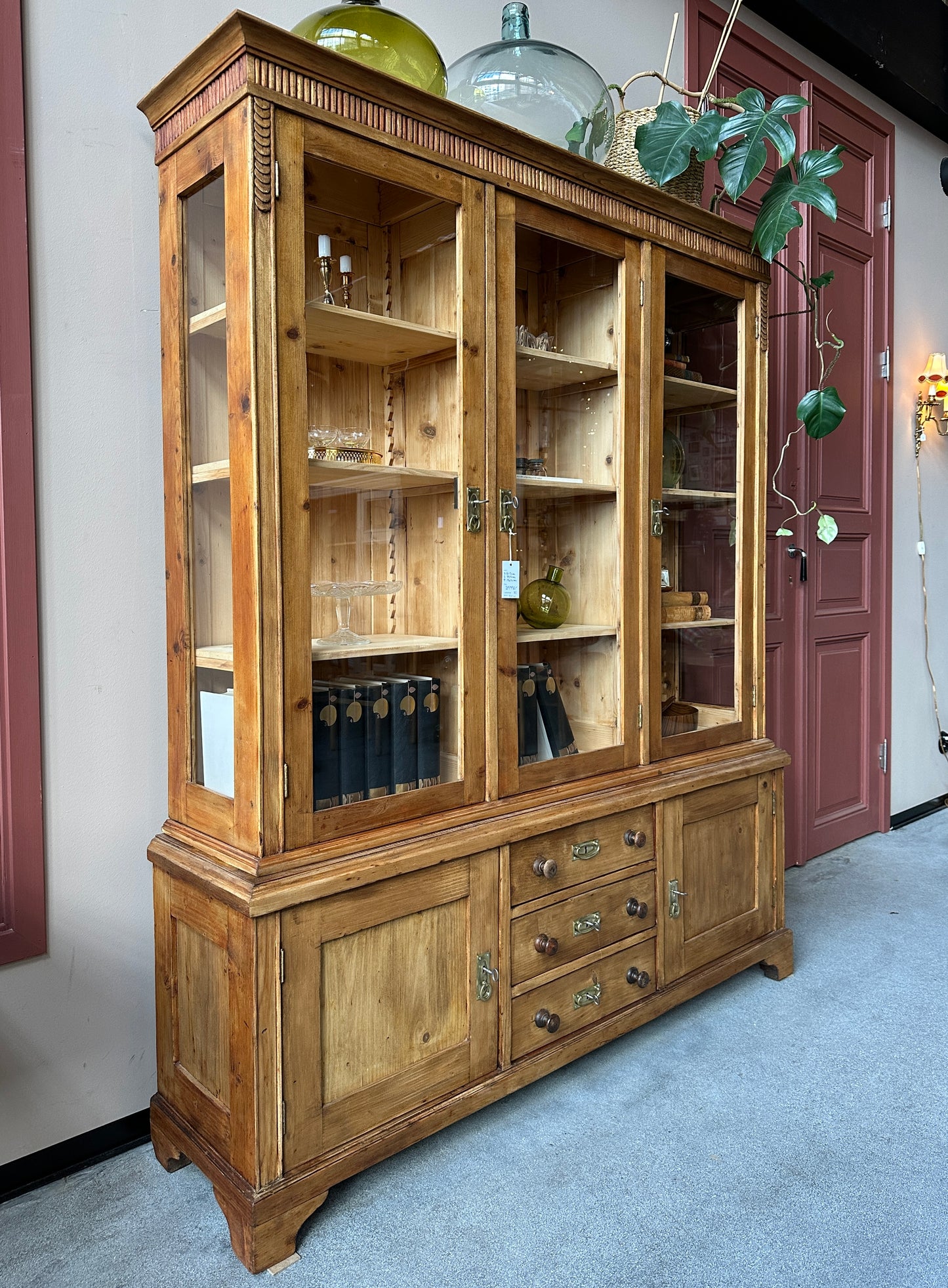 Ett gammalt omålat vitrinskåp som med sin fina patina skapar en varm känsla i rummet. Skåpet har fina proportioner och det har både täckta och glasade dörrar samt glas i sidan för vackert ljusinsläpp