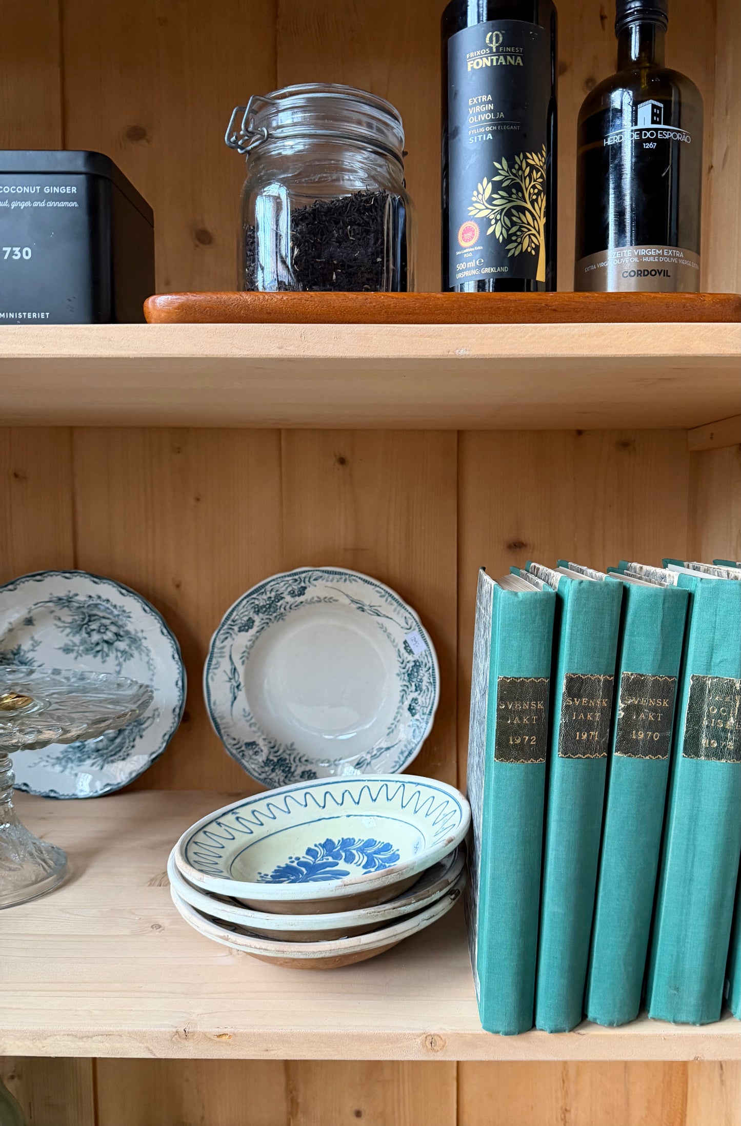 Ett gammalt vackert vitrinskåp med både runda och raka former i Dakaboms mörka grågröna färg.