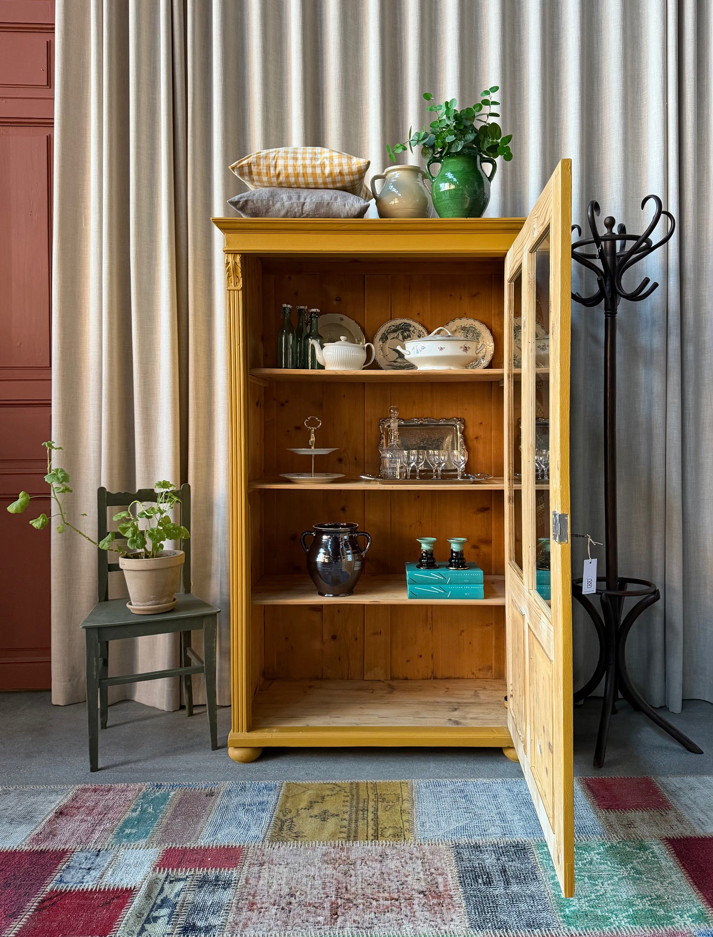 Ett gammalt vackert vitrinskåp med två vitrin glas och täckt spegel nedtill. Skåpet har en högerhängd dörr och fina detaljer.