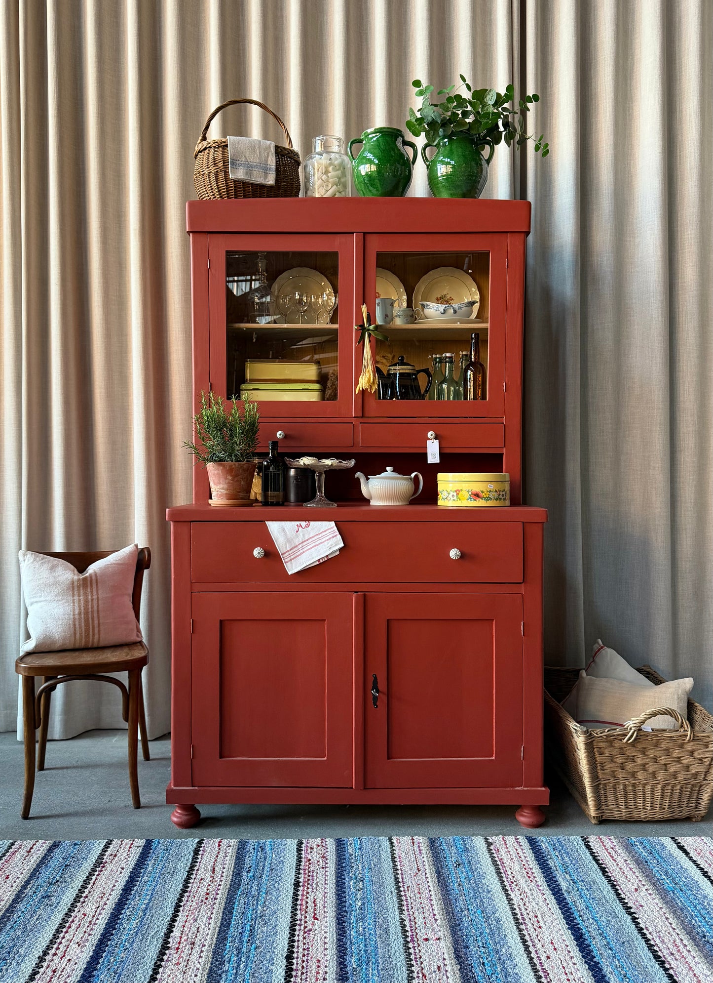 Ett gammalt, vackert och charmigt köksskåp i varmröd kulör med härlig utformning.