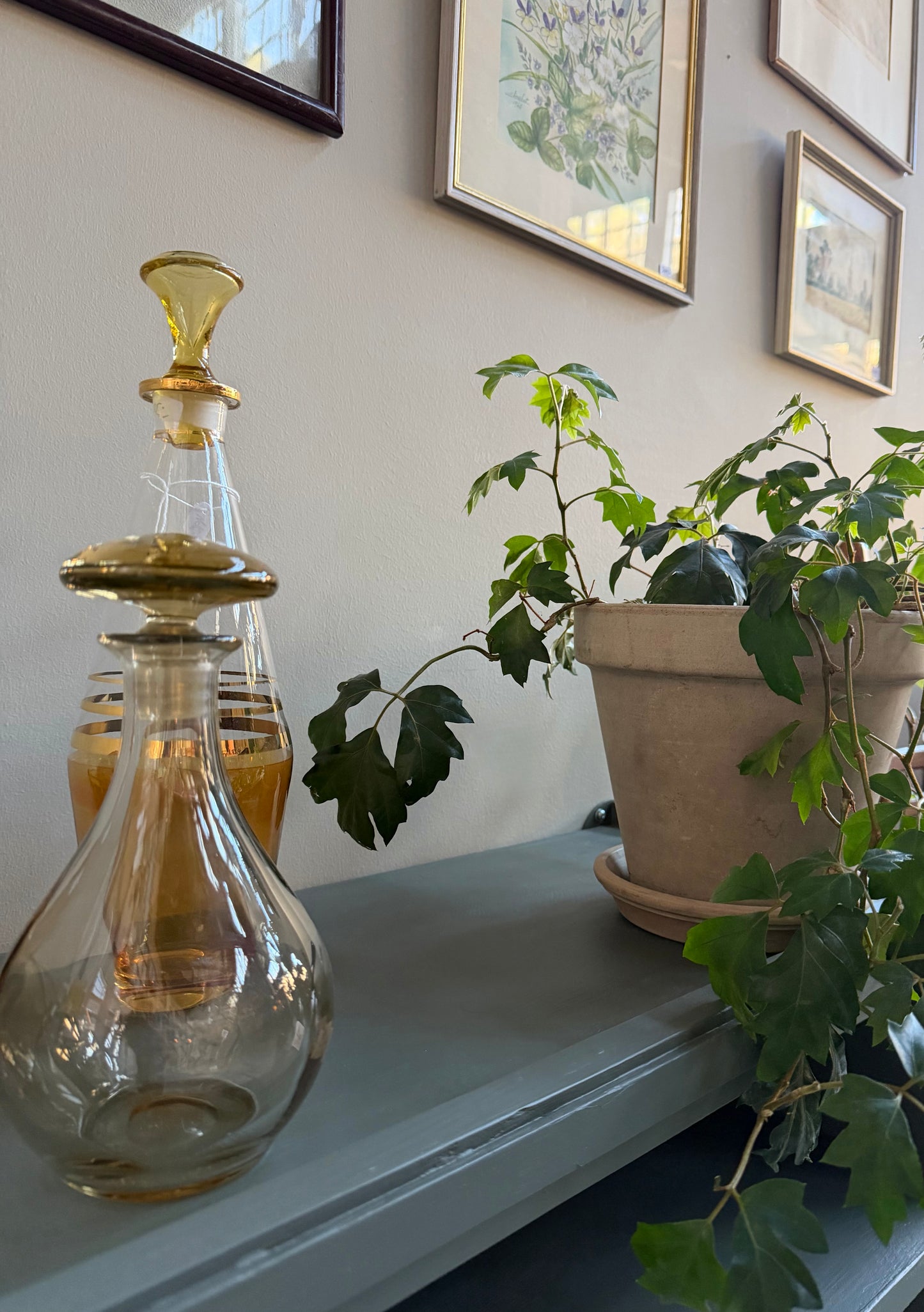 Denna tv-bänk/vägghängda hylla är nytillverkad i massiv furu på vårt snickeri i Ungern. Slutligen är den penselmålad med en matt vattenbaserad snickerifärg i Dakaboms mörka grå/gröna kulör. Väldigt fint att ha både tv-bänk och vitrinskåp i samma kulör, det blir en röd tråd och knyter ihop rummet fantastiskt fint.