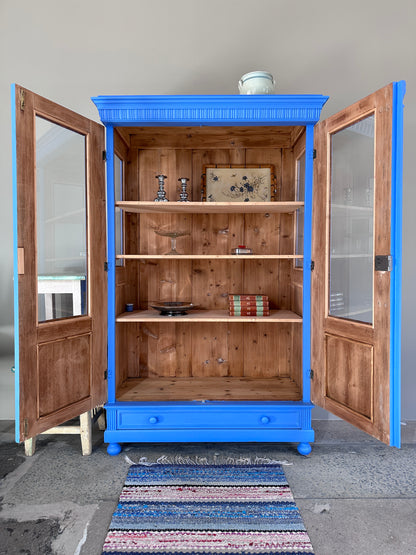 Bild visar blått vitrinskåp med två öppna dörrar