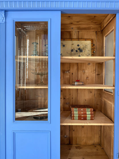 Bild visar blått vitrinskåp med två dörrar, varav en öppen
