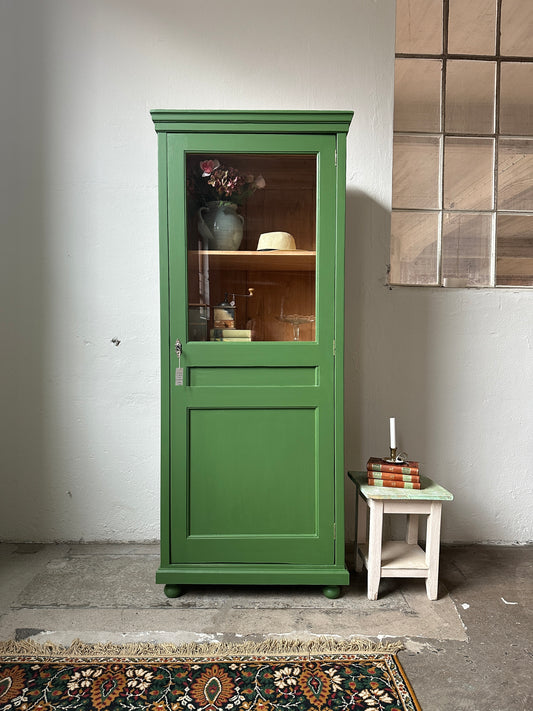 Bild visar ett grönt vitrinskåp med en dörr