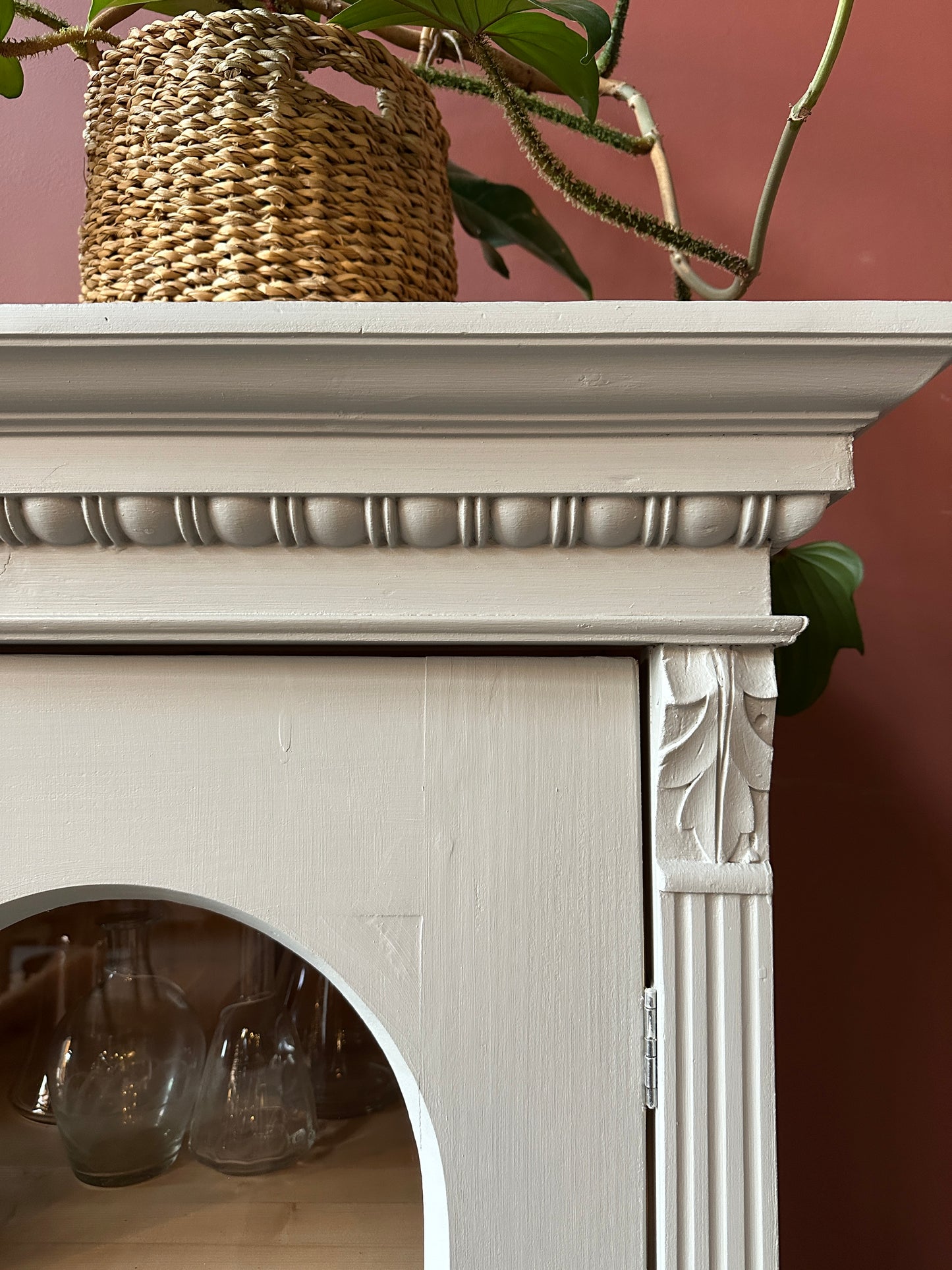 Detaljbild på krön vitrinskåp.