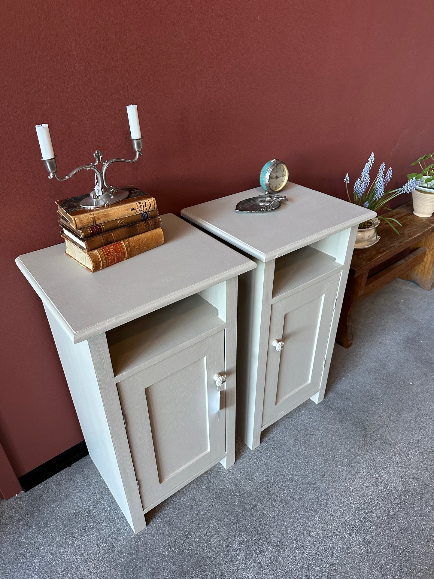 2 st ljusa sängbord mot röd vägg