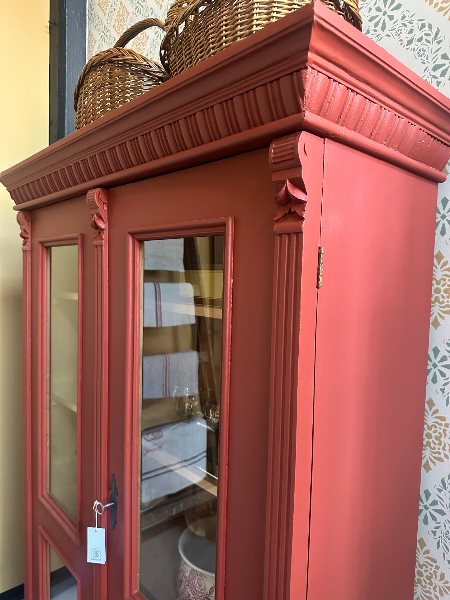 rött vitrinskåp mot tapetserad vägg