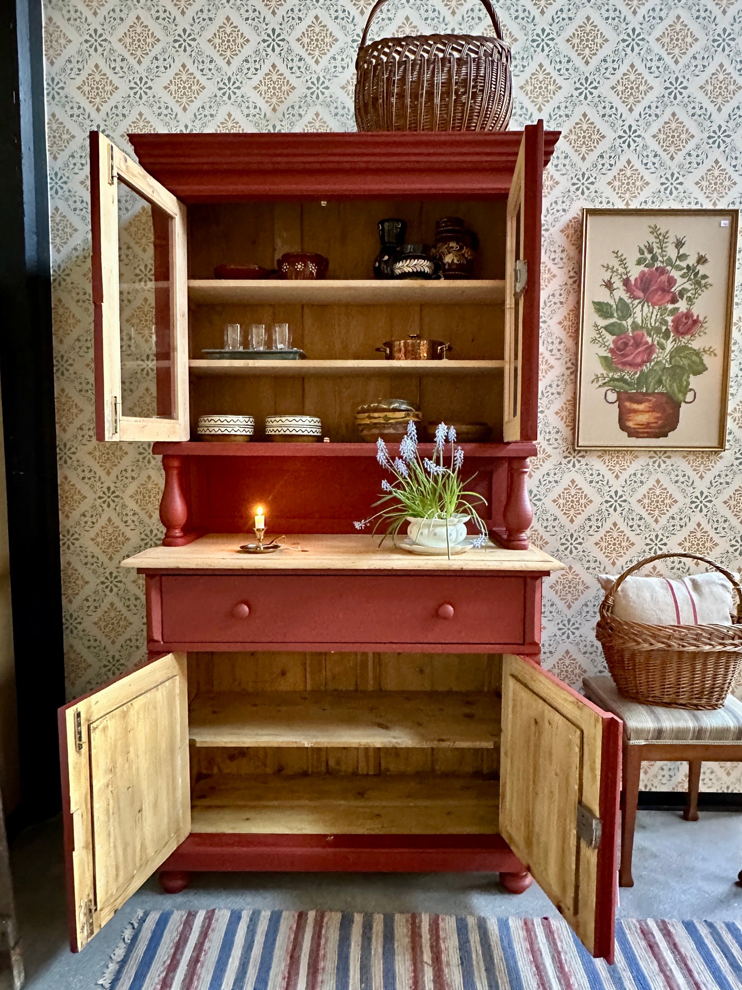 Ett rött köksskåp mot tapetserad vägg