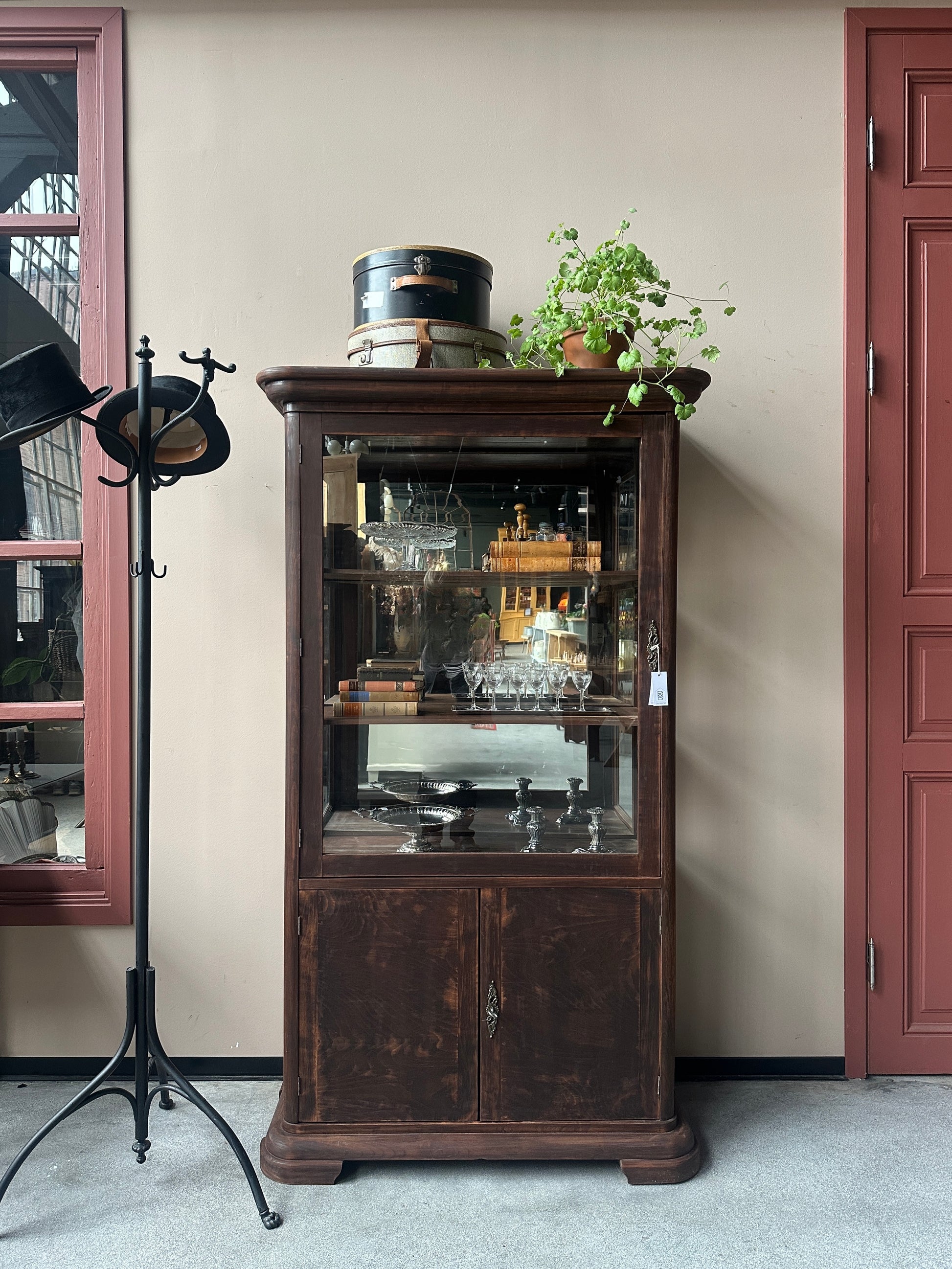Ett gammalt, elegant vitrinskåp/displayskåp med en rundad frontdesign och med ett stort glas i den övre delen av dörren