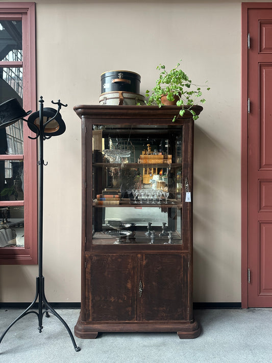 Ett gammalt, elegant vitrinskåp/displayskåp med en rundad frontdesign och med ett stort glas i den övre delen av dörren