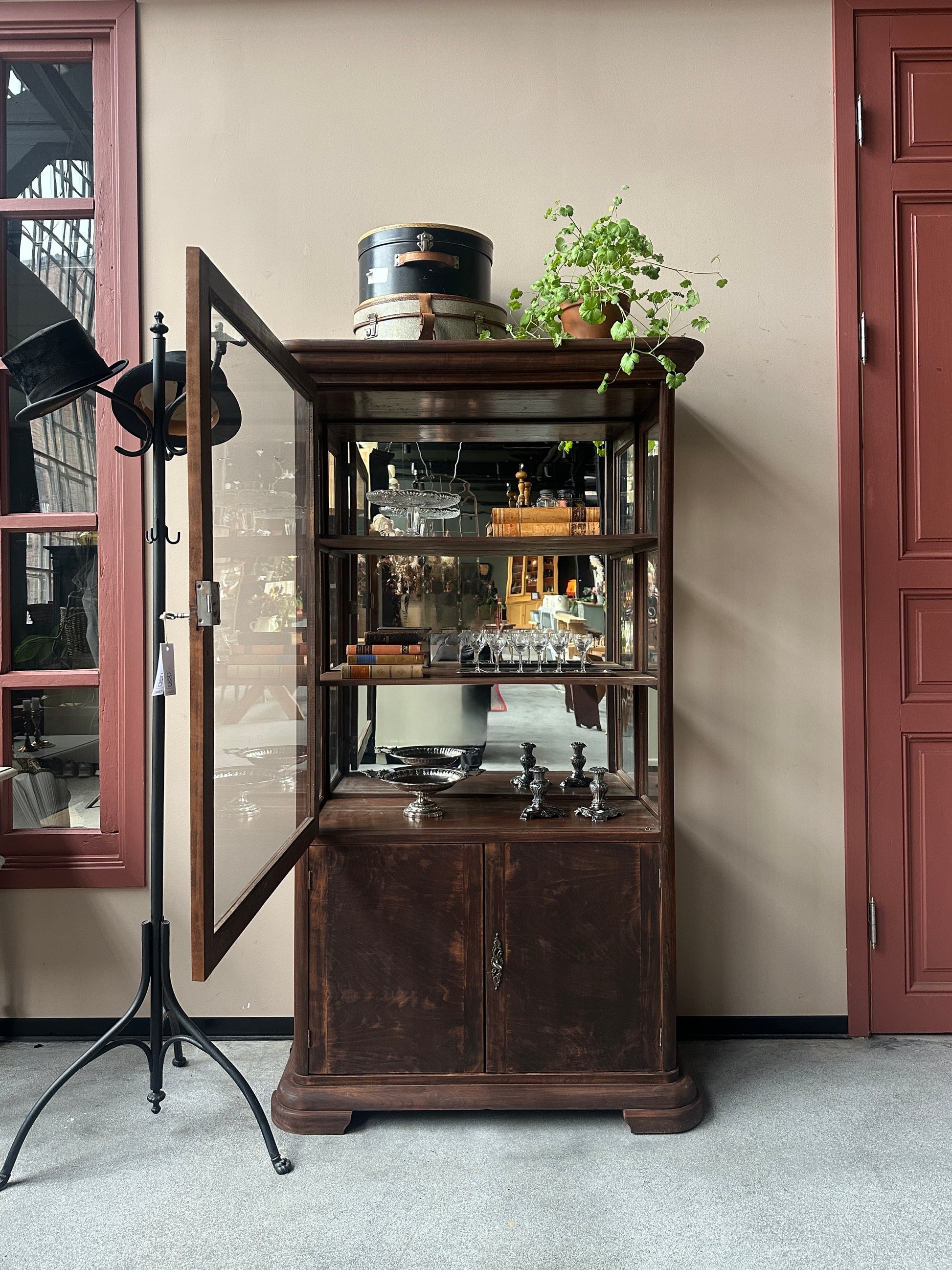 Ett gammalt, elegant vitrinskåp/displayskåp med en rundad frontdesign och med ett stort glas i den övre delen av dörren