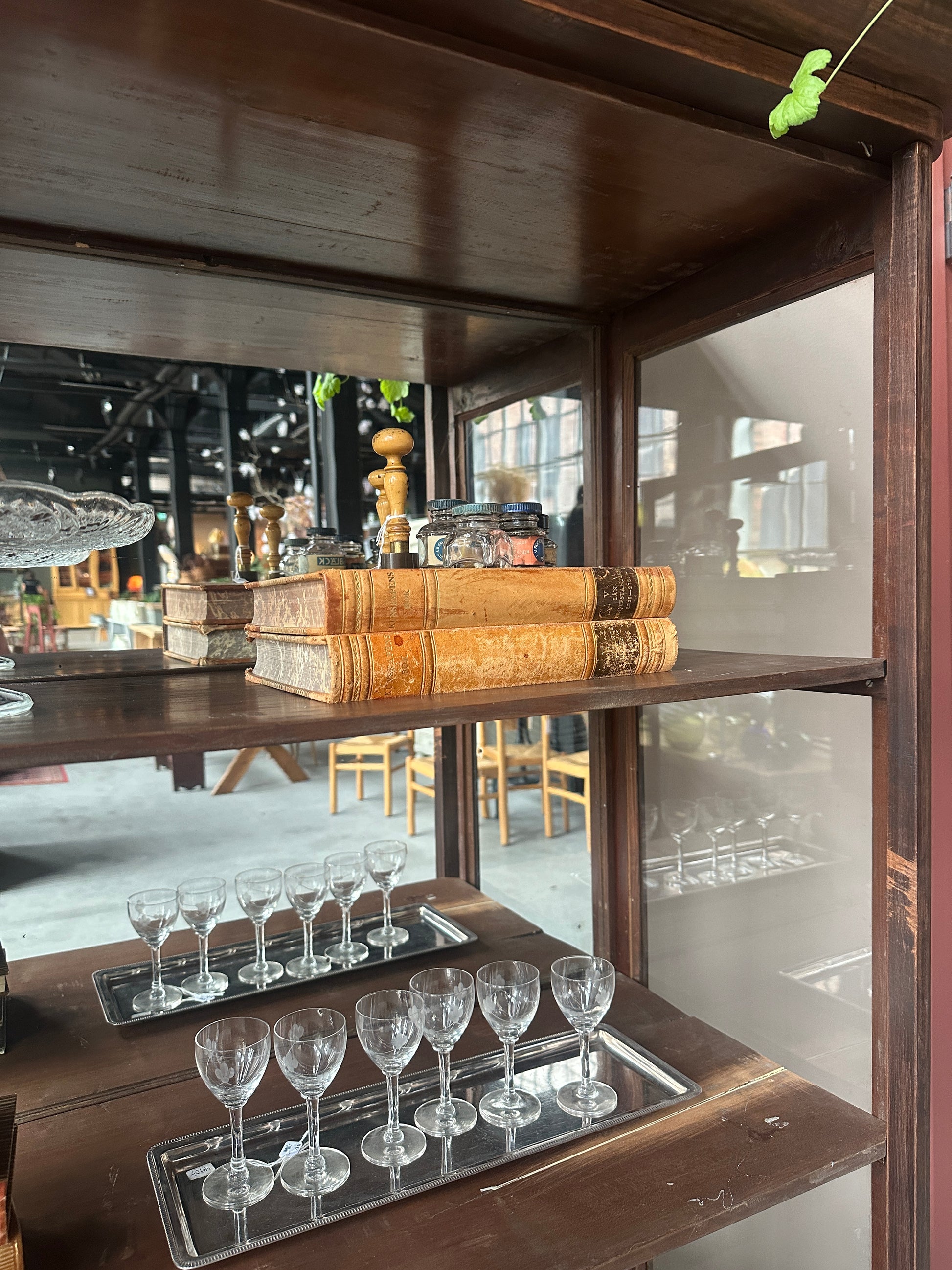 Ett gammalt, elegant vitrinskåp/displayskåp med en rundad frontdesign och med ett stort glas i den övre delen av dörren