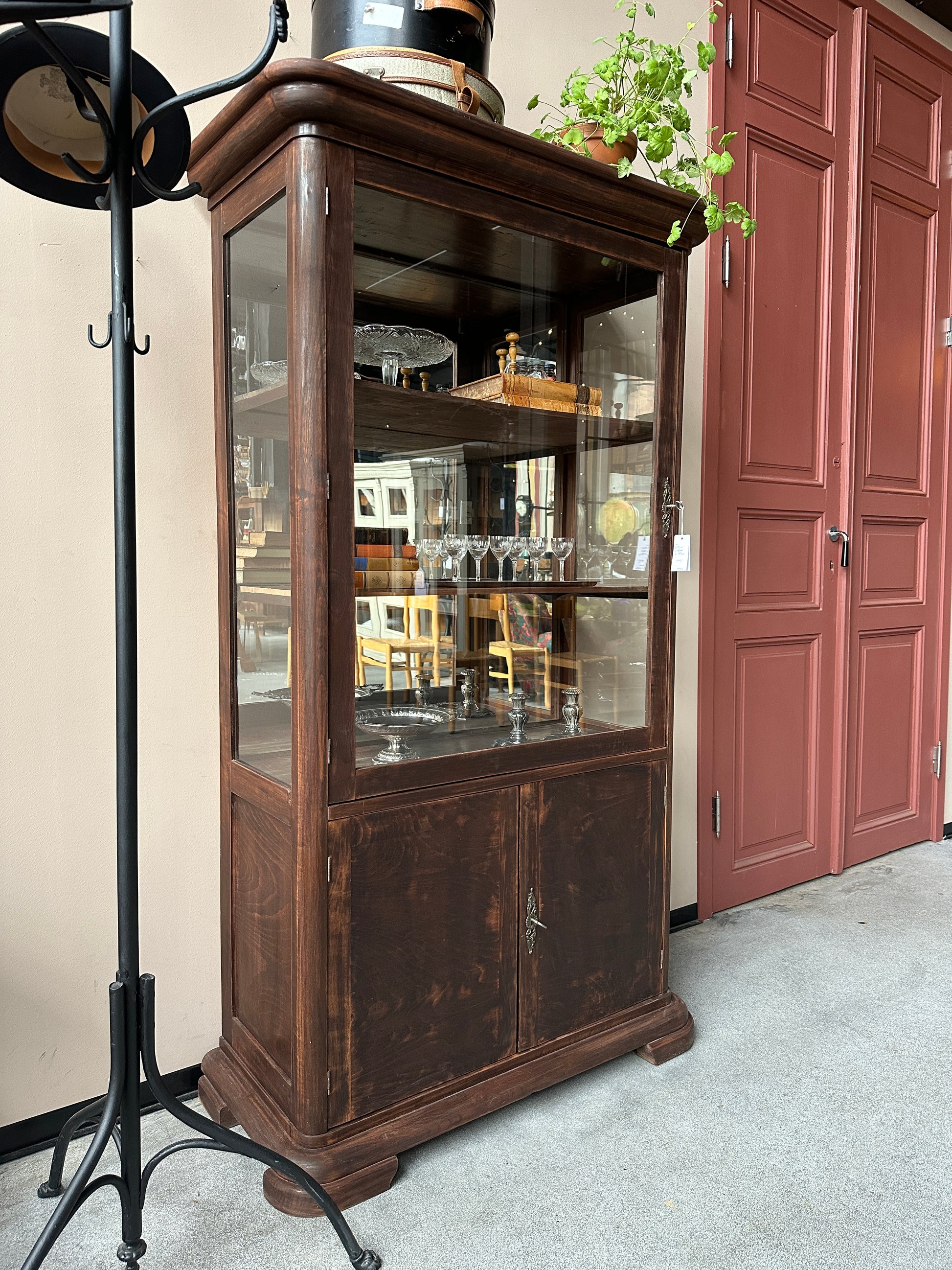 Ett gammalt, elegant vitrinskåp/displayskåp med en rundad frontdesign och med ett stort glas i den övre delen av dörren