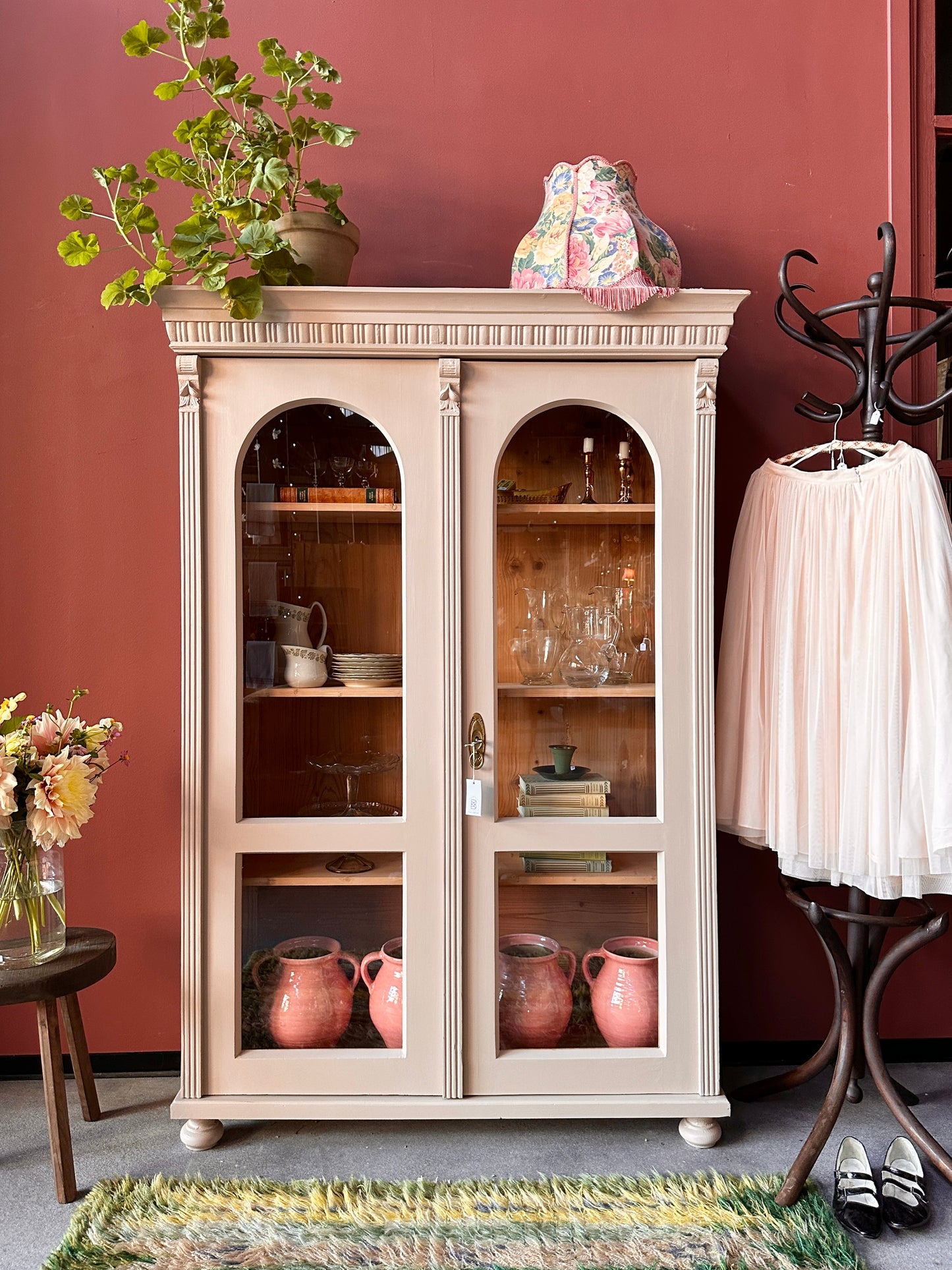 Ett vackert gammalt vitrinskåp med utsmyckade detaljer och rundade vitringlas utmed halva dörrarna.