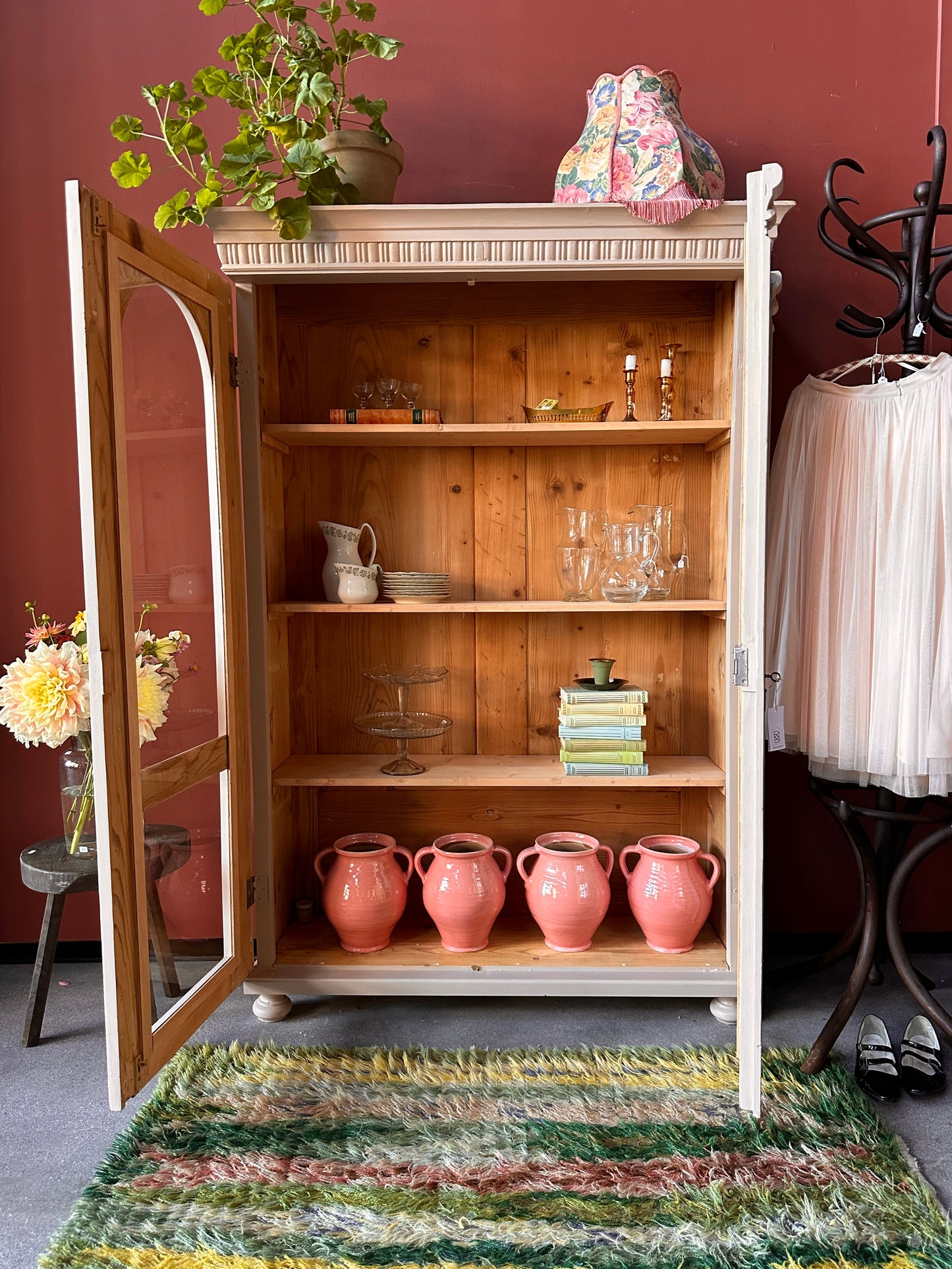 Ett vackert gammalt vitrinskåp med utsmyckade detaljer och rundade vitringlas utmed halva dörrarna.