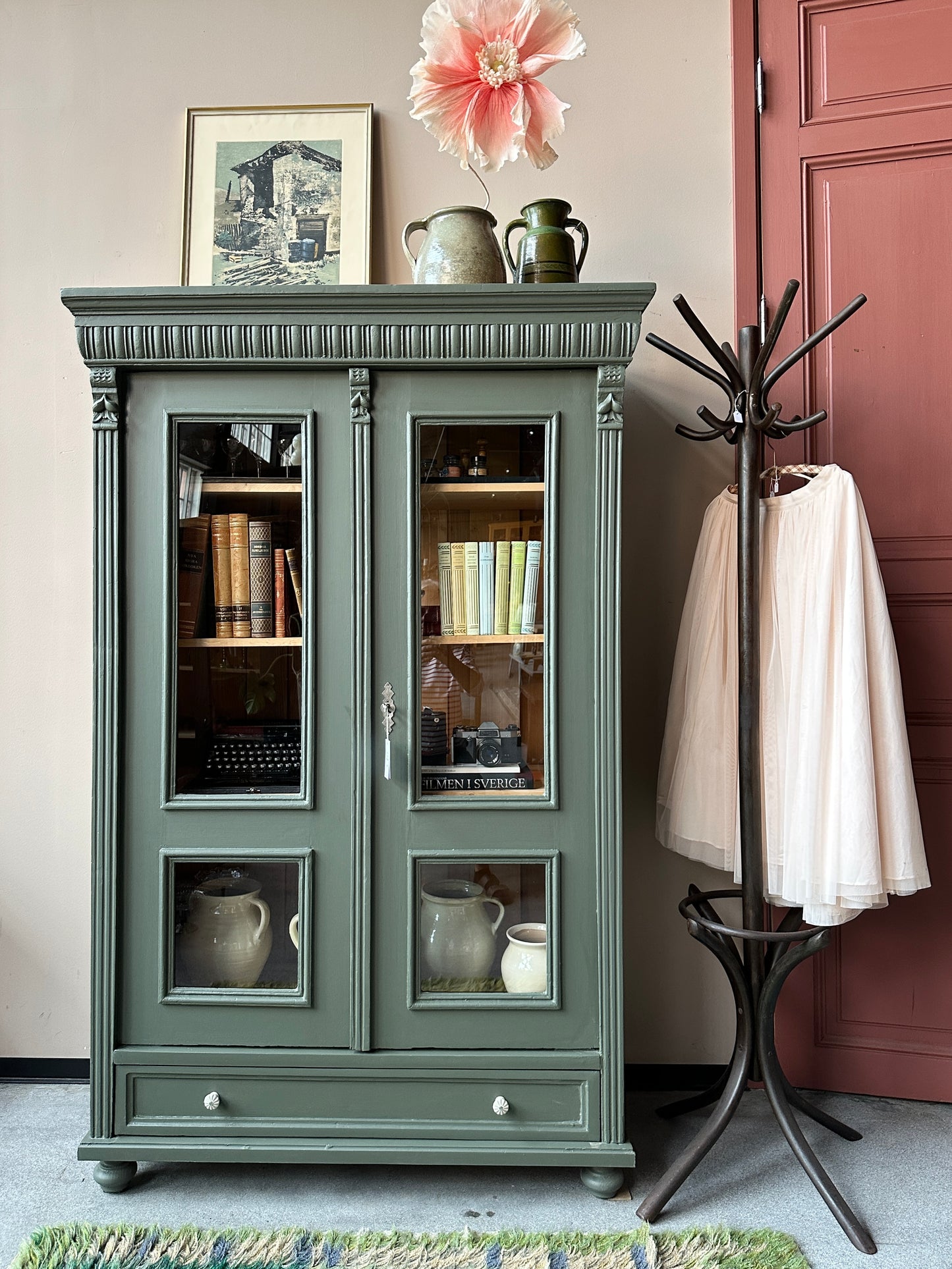 Ett gammalt vackert vitrinskåp med vackra detaljer. Skåpet har en bred praktiskt låda nertill med nya porslinsknoppar i äldre stil.