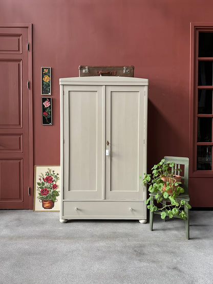 Ett gammalt vackert linneskåp med raka former och färre detaljer. Det har en praktisk låda längst ner med inmålade knoppar i trä