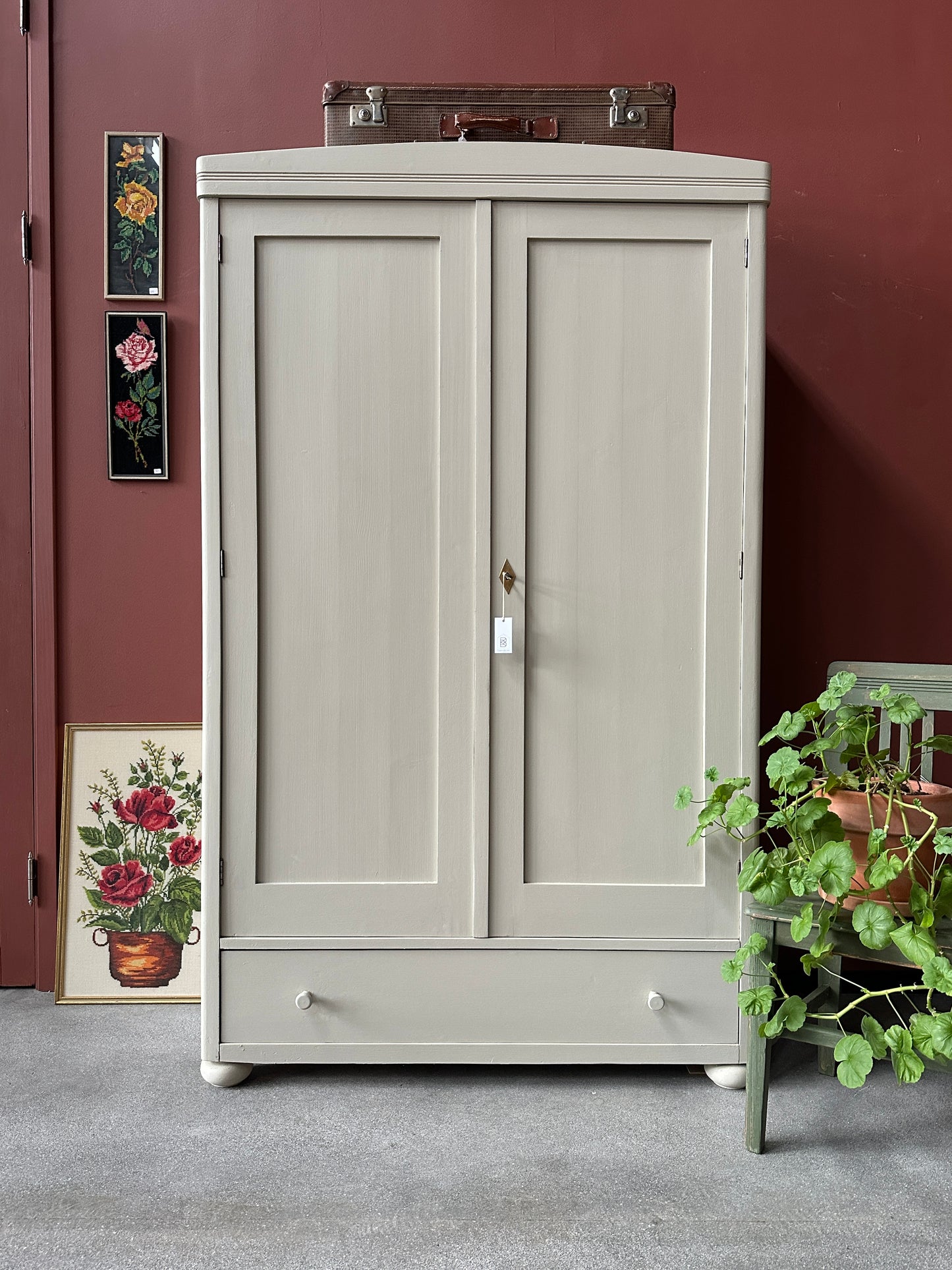 Ett gammalt vackert linneskåp med raka former och färre detaljer. Det har en praktisk låda längst ner med inmålade knoppar i trä