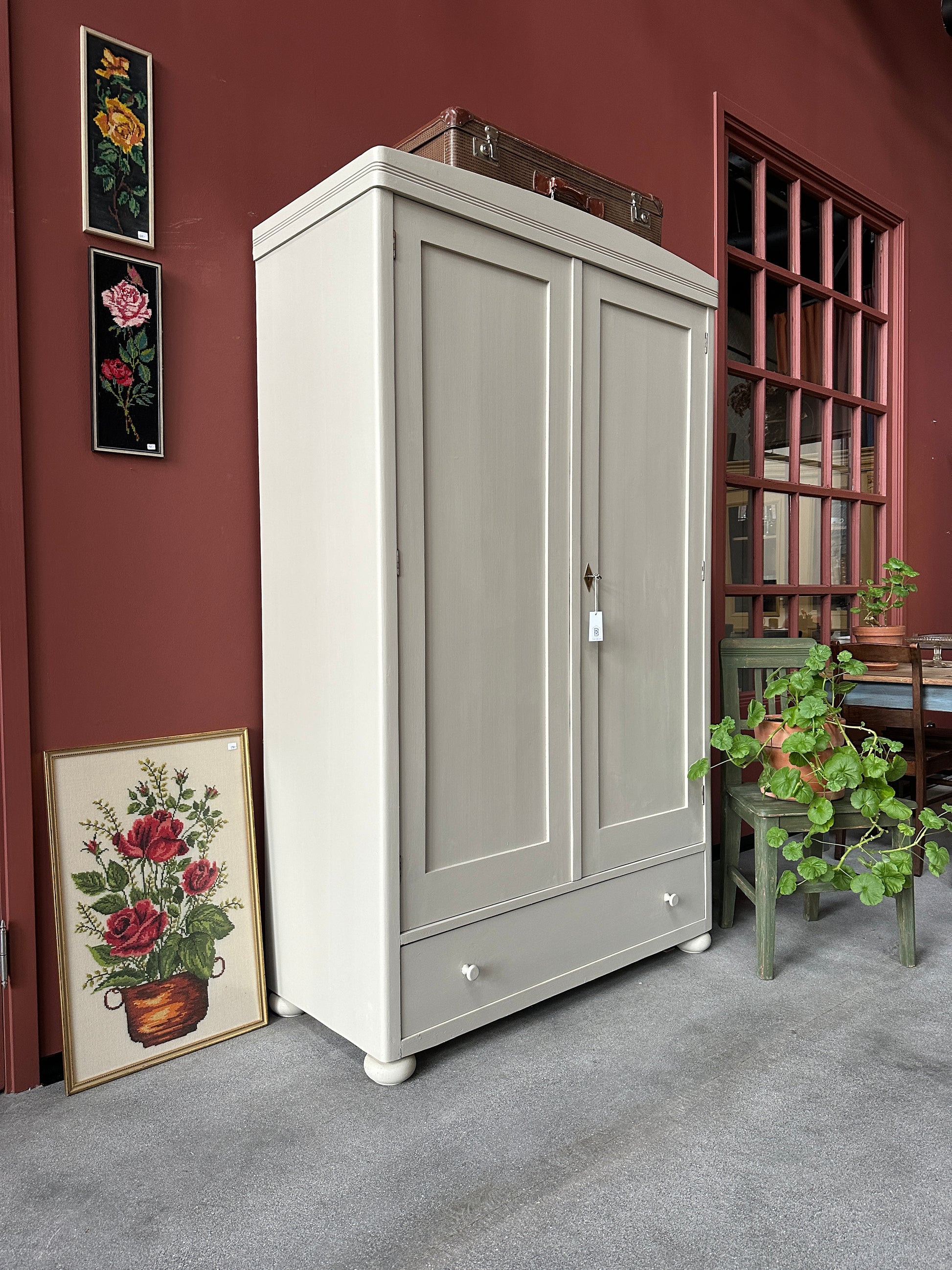 Ett gammalt vackert linneskåp med raka former och färre detaljer. Det har en praktisk låda längst ner med inmålade knoppar i trä