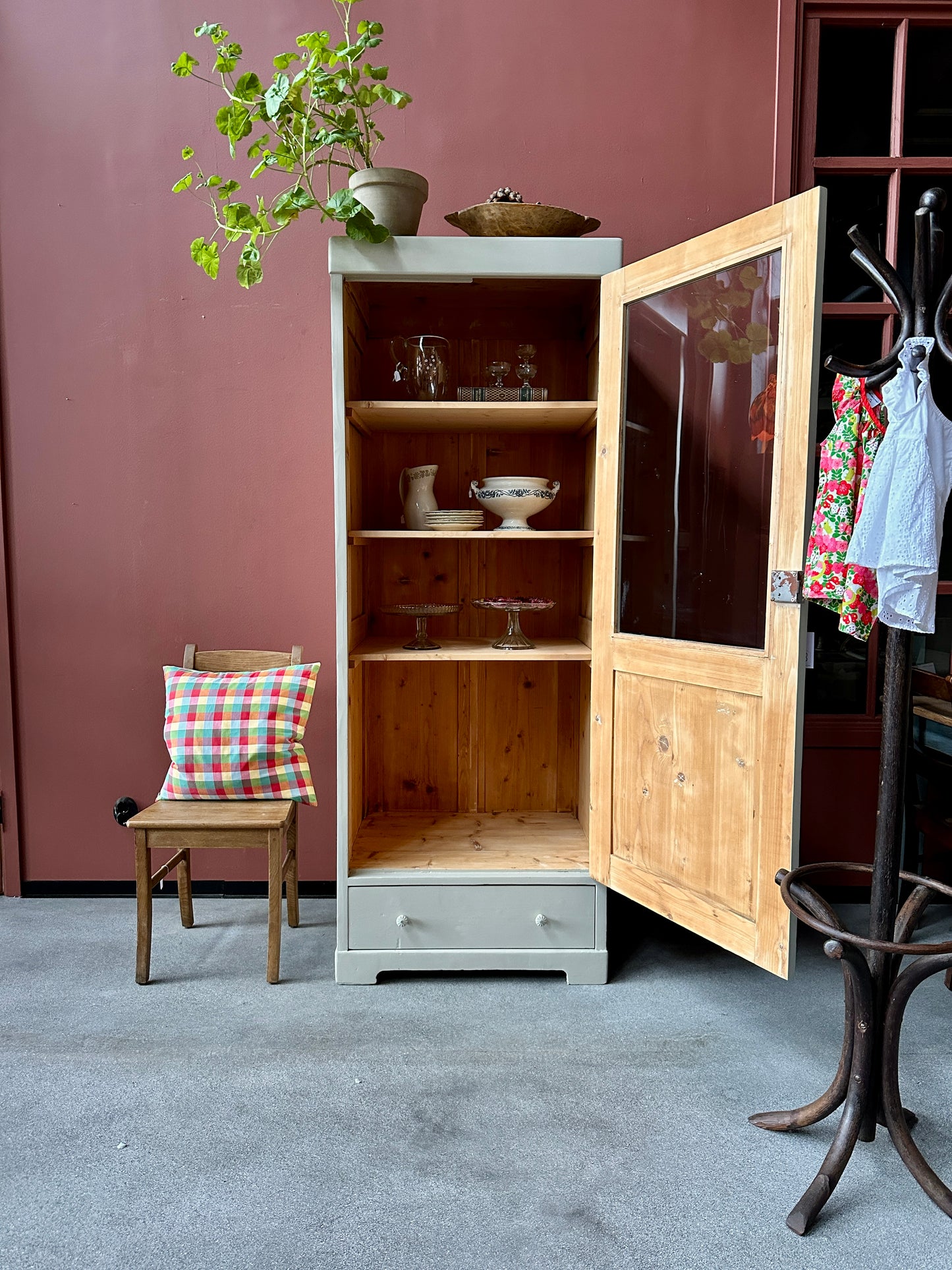 ett greige vitrinskåp mot röd vägg