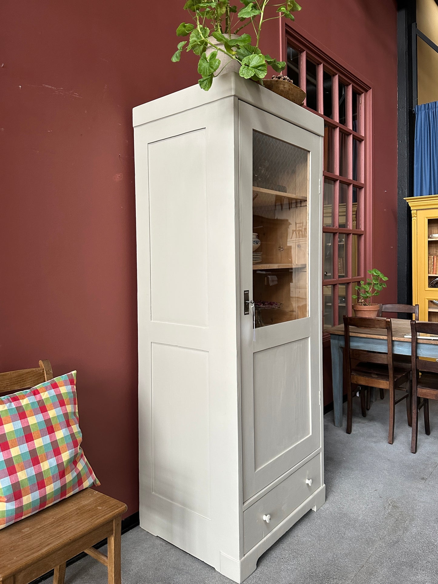 ett greige vitrinskåp mot röd vägg