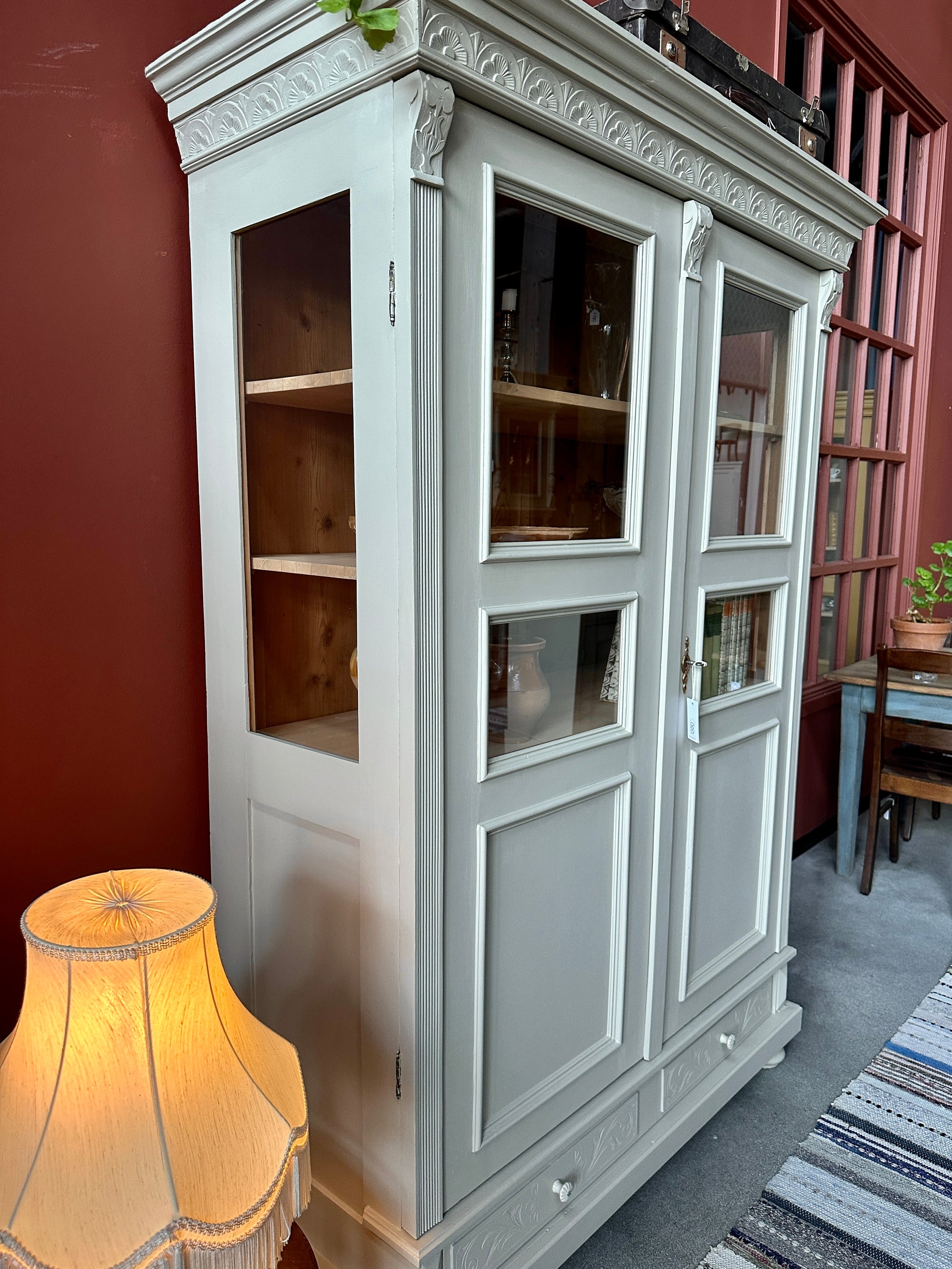 Ett gammalt vackert vitrinskåp med många vackra detaljer. Skåpet har glas i de fyra övre speglarna och täckt nertill för praktiskt dold förvaring