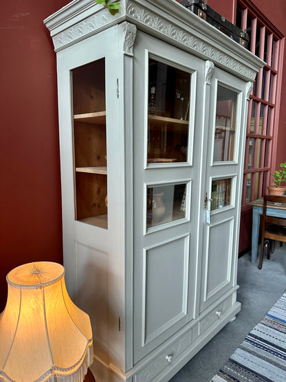 Ett gammalt vackert vitrinskåp med många vackra detaljer. Skåpet har glas i de fyra övre speglarna och täckt nertill för praktiskt dold förvaring