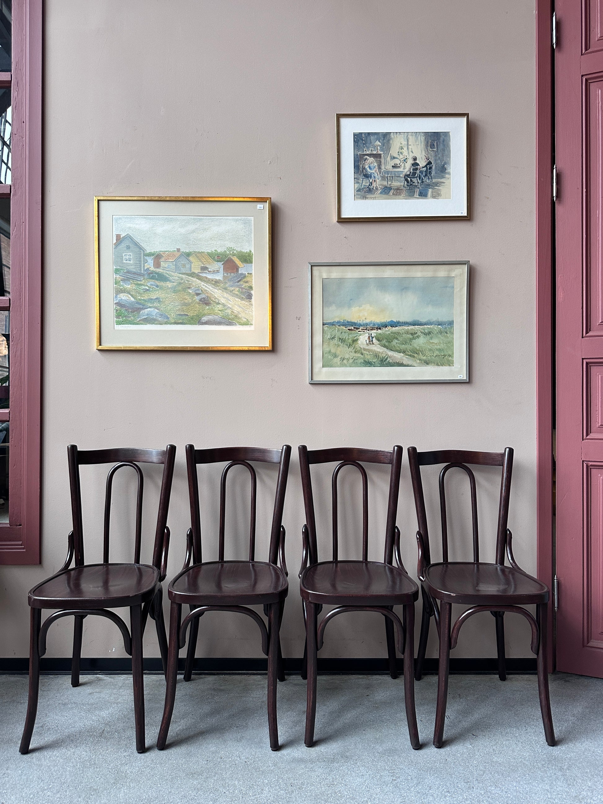 4 st bruna stolar mot en vägg med 3 st tavlor.