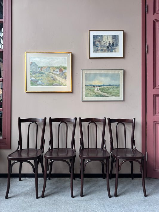 4 st bruna stolar mot en vägg med 3 st tavlor.