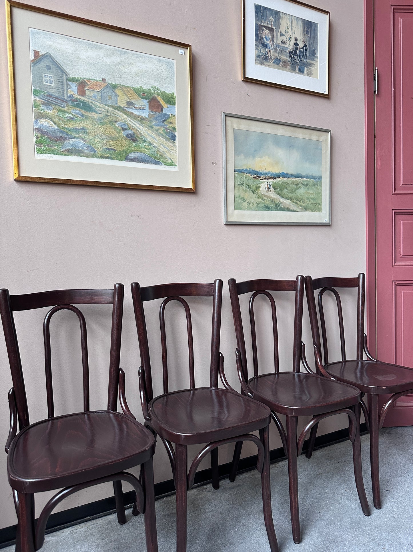 4 st bruna stolar mot en vägg med 3 st tavlor.