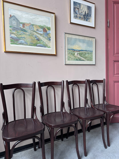 4 st bruna stolar mot en vägg med 3 st tavlor.