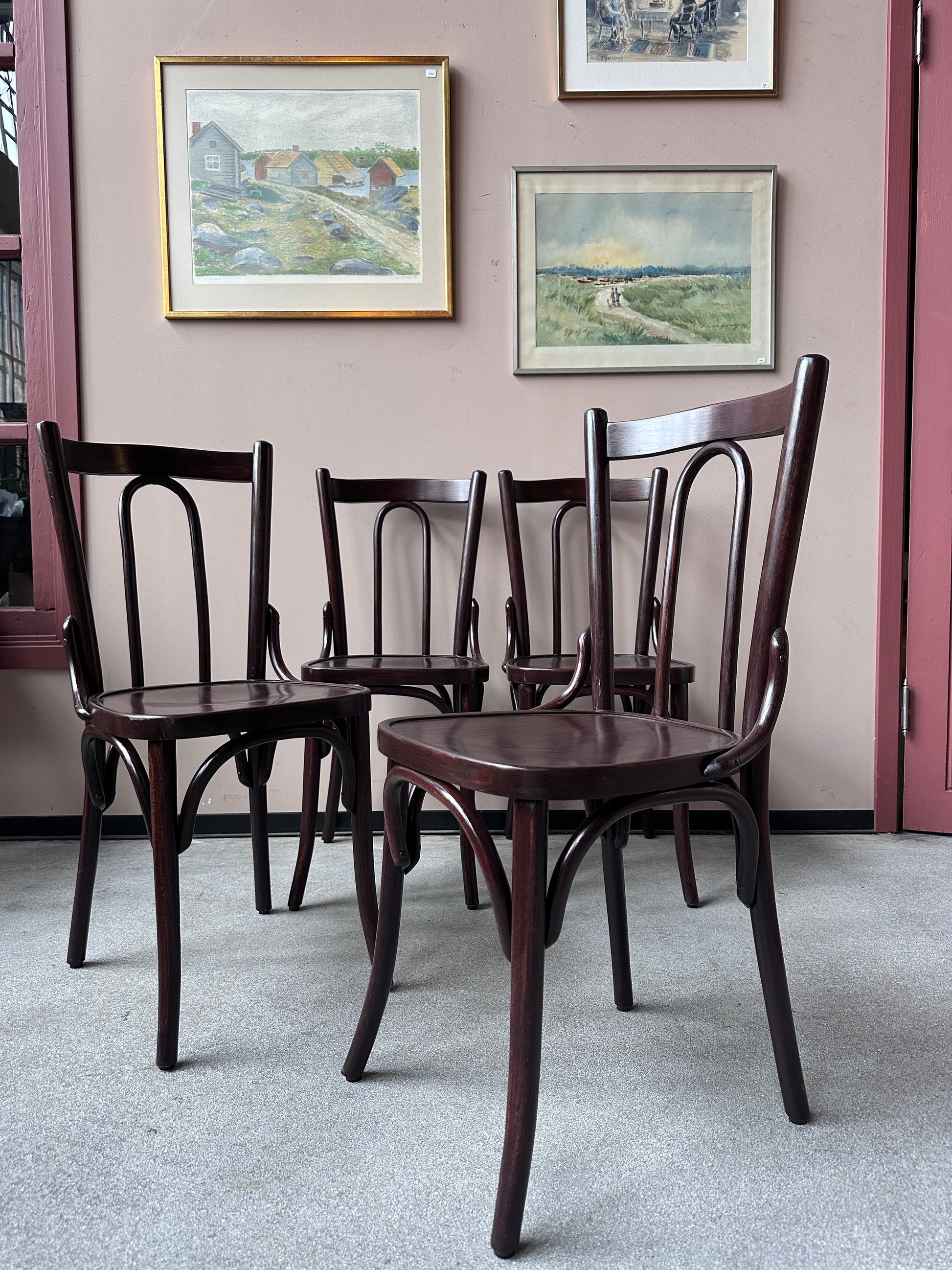 4 st bruna stolar mot en vägg med 3 st tavlor.