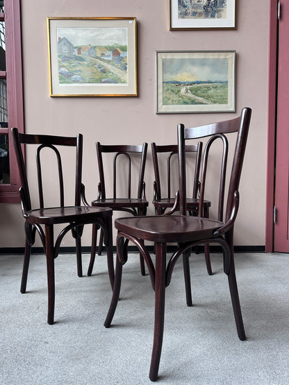 4 st bruna stolar mot en vägg med 3 st tavlor.