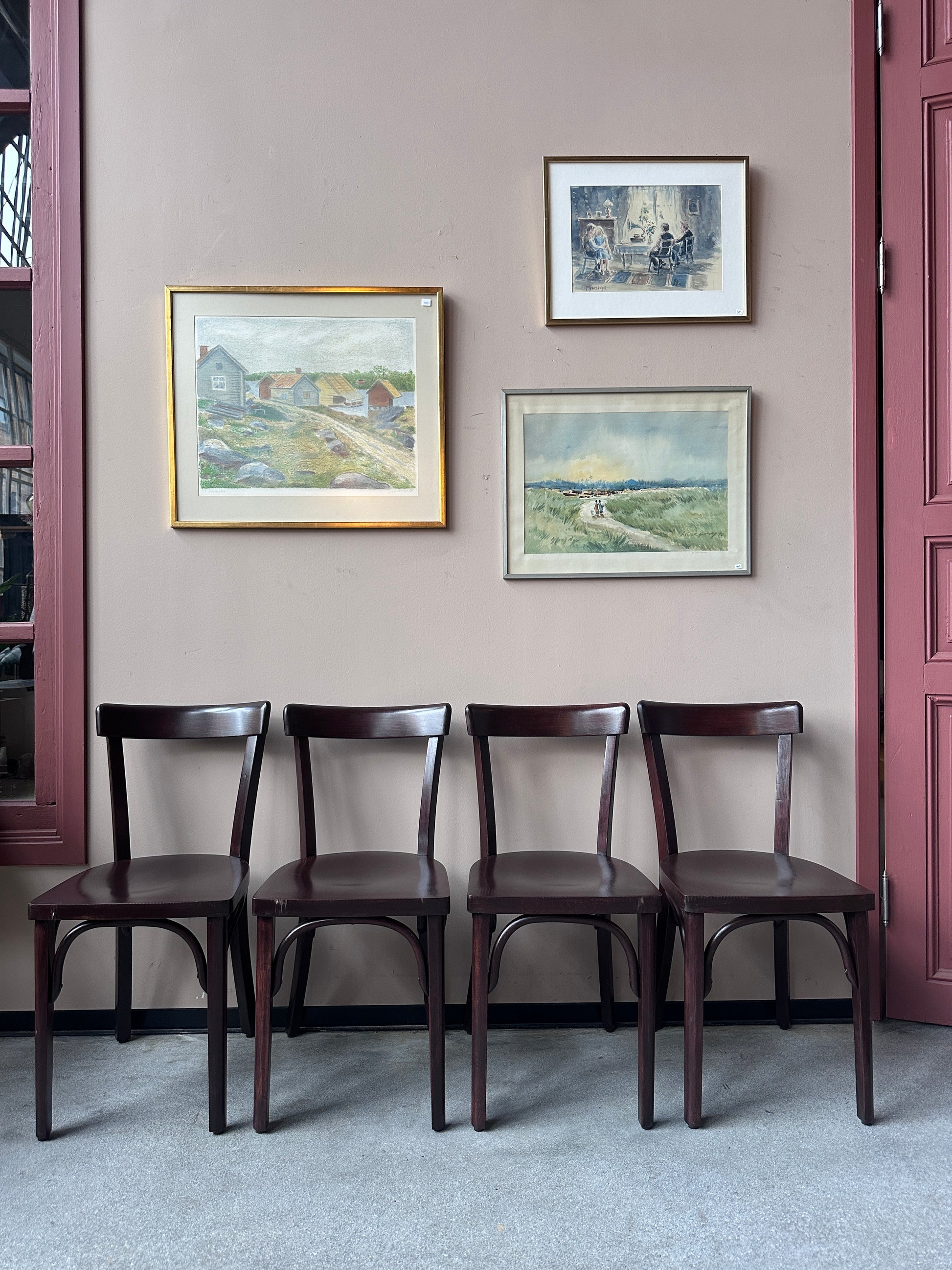 4 st bruna stolar mot en vägg med 3 st tavlor.
