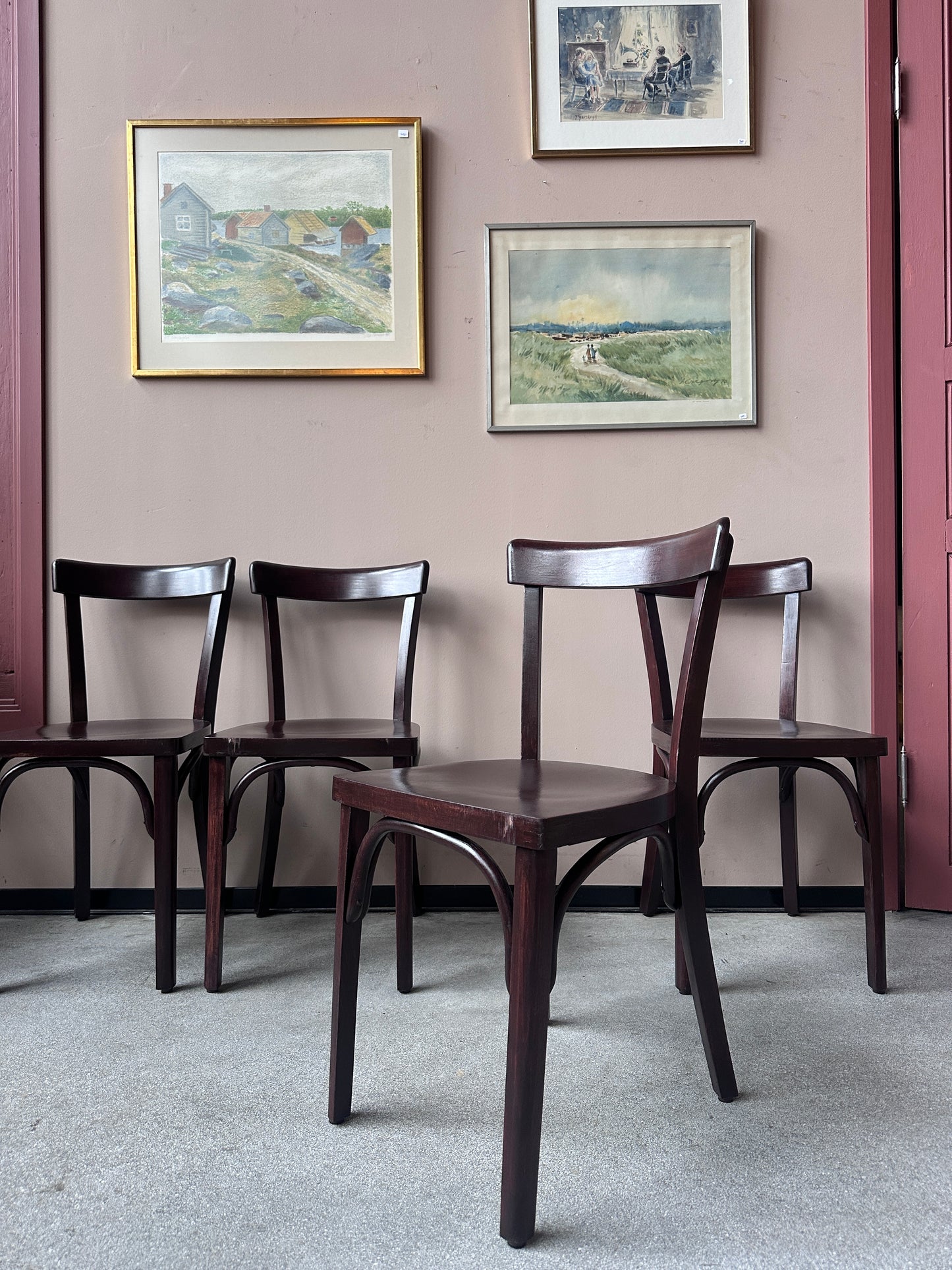 4 st bruna stolar mot en vägg med 3 st tavlor.