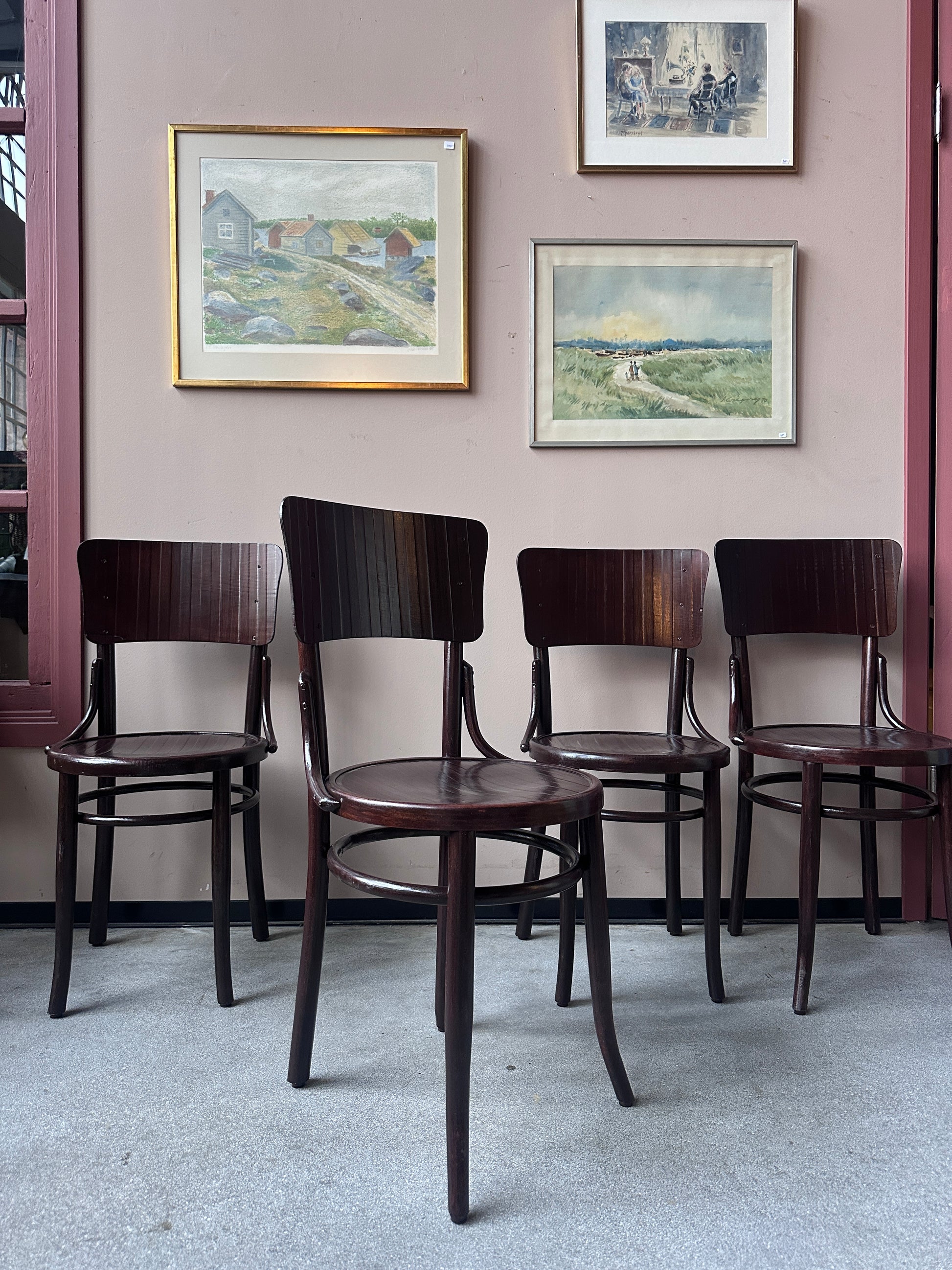 4 st stolar mot en vägg med 3 st tavlor. 