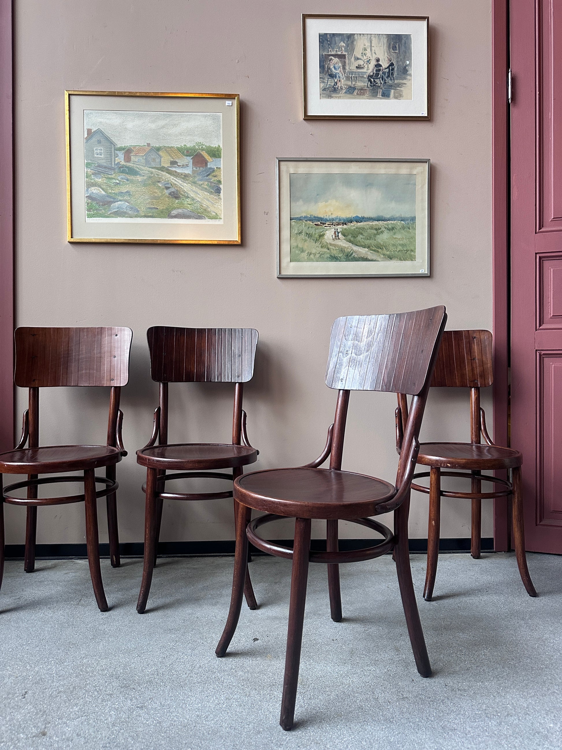 4 st stolar mot en vägg med 3 st tavlor. 