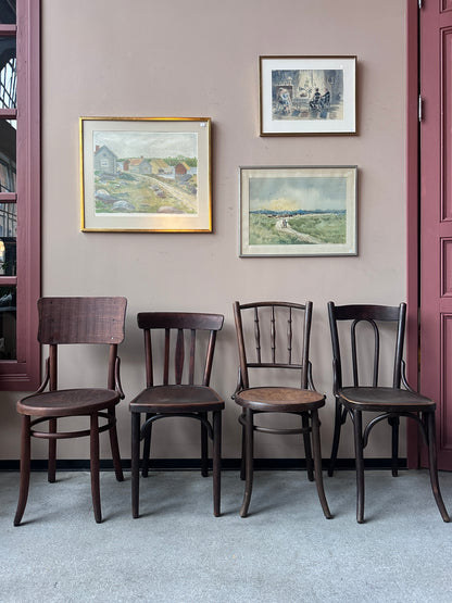 4 st bruna stolar i olika modeller. Stolarna står mot en vägg med 3 st tavlor. 