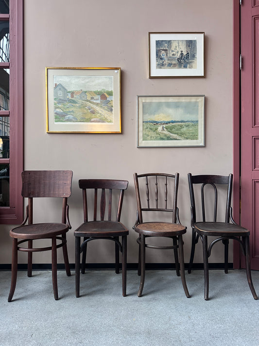 4 st bruna stolar i olika modeller. Stolarna står mot en vägg med 3 st tavlor. 