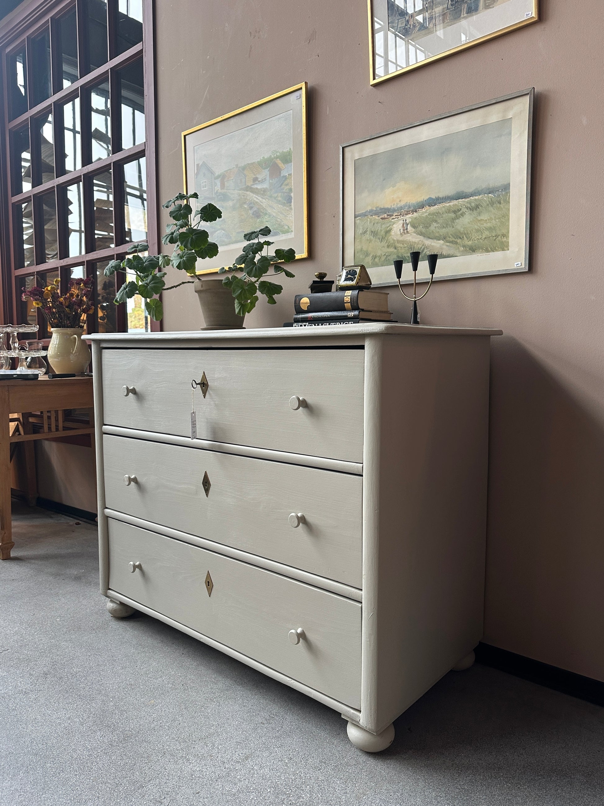 En gammal, vacker byrå i större mått med massor av förvaring. Den har 3 st praktiska lådor med inmålade träknoppar.