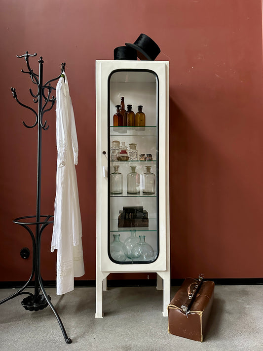 Ett gammalt läckert läkarskåp med fyra hyllor i glas och även glas i sidan.&nbsp;
Skåpet är i stål och lackat vitt