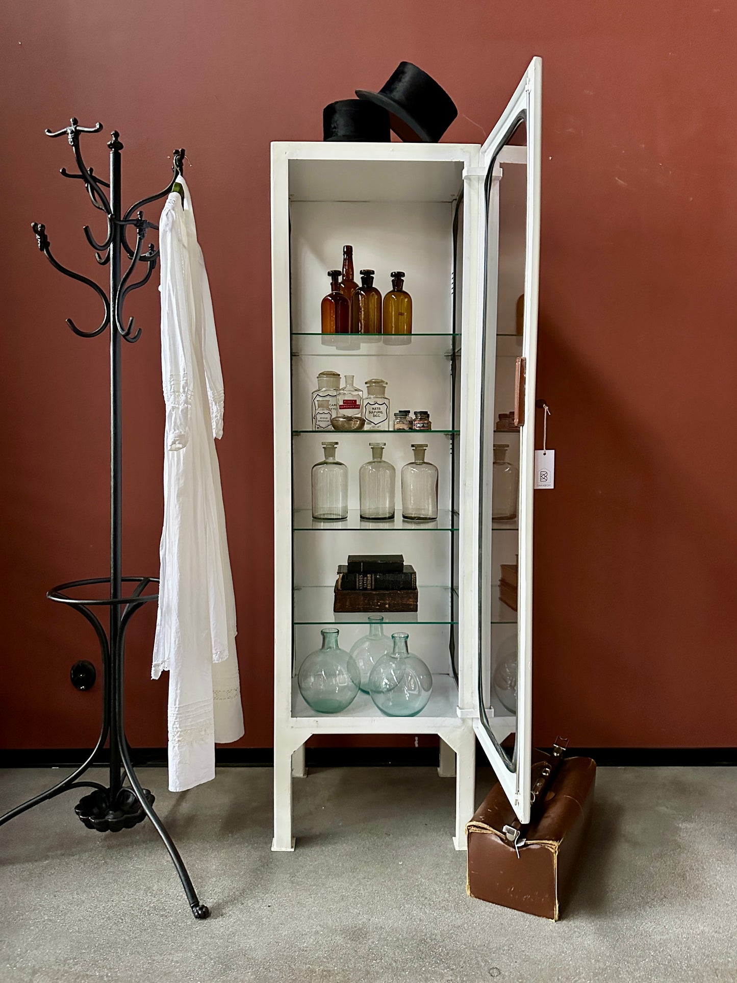 Ett gammalt läckert läkarskåp med fyra hyllor i glas och även glas i sidan.&nbsp;
Skåpet är i stål och lackat vitt