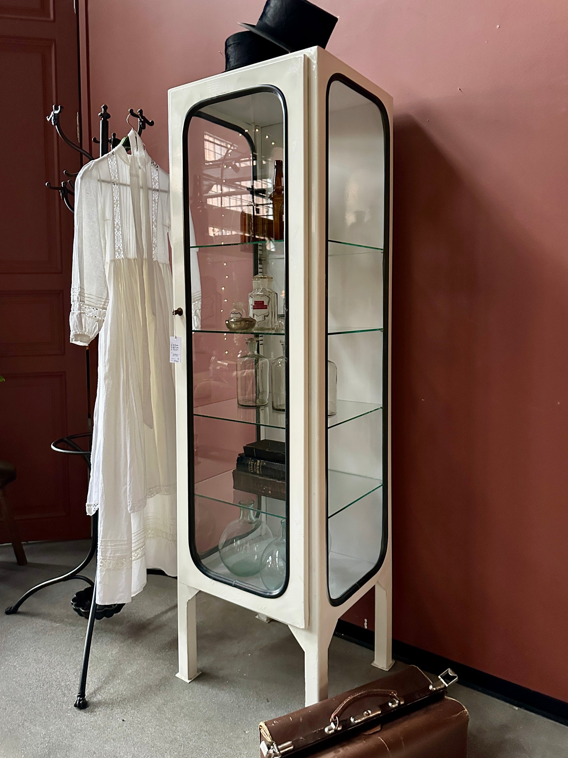 Ett gammalt läckert läkarskåp med fyra hyllor i glas och även glas i sidan.&nbsp;
Skåpet är i stål och lackat vitt