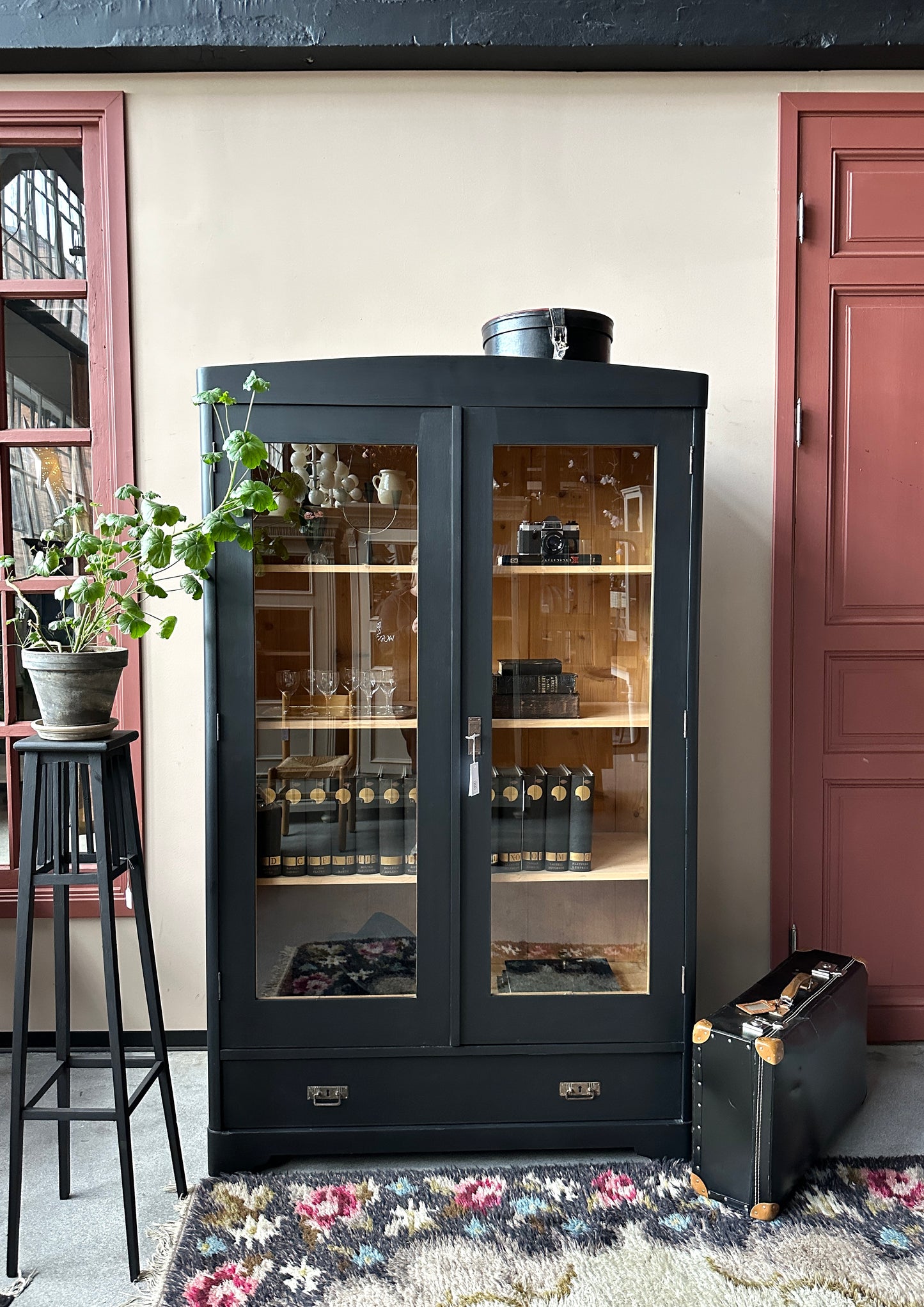 Ett gammalt, vackert vitrinskåp med rundad överkant.Skåpet har två glasdörrar. 