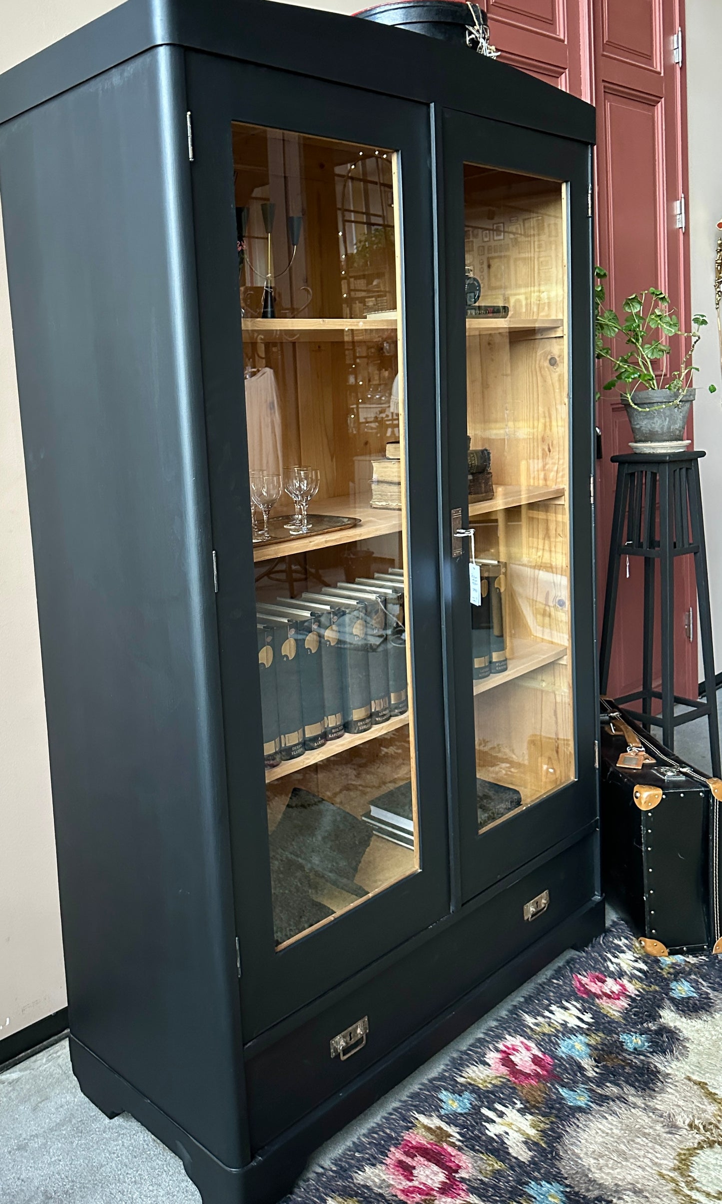 Ett gammalt, vackert vitrinskåp med rundad överkant.Skåpet har två glasdörrar. 