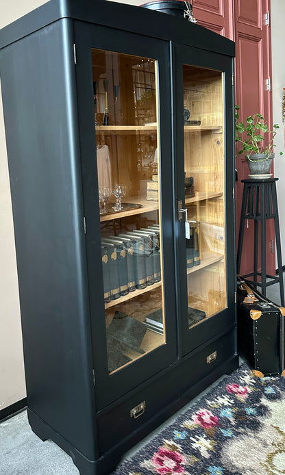 Ett gammalt, vackert vitrinskåp med rundad överkant.Skåpet har två glasdörrar. 