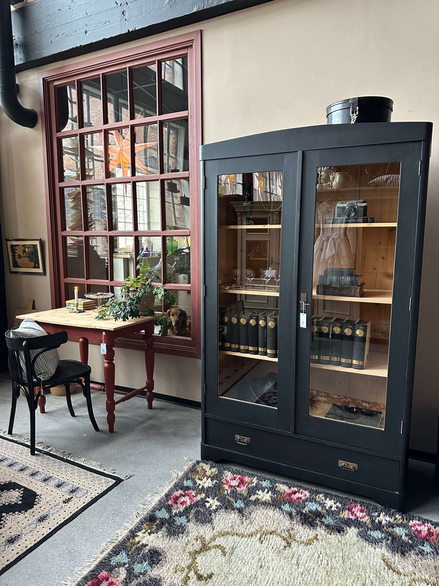 Ett gammalt, vackert vitrinskåp med rundad överkant.Skåpet har två glasdörrar. 