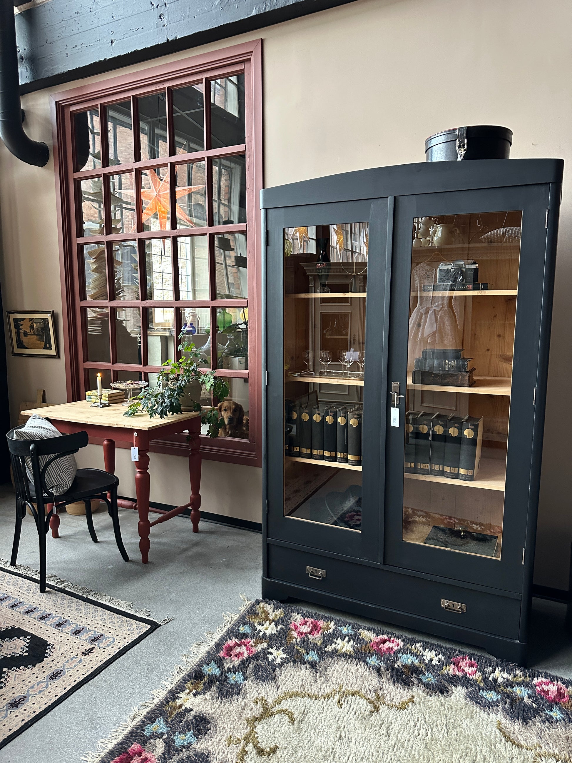 Ett gammalt, vackert vitrinskåp med rundad överkant.Skåpet har två glasdörrar. 