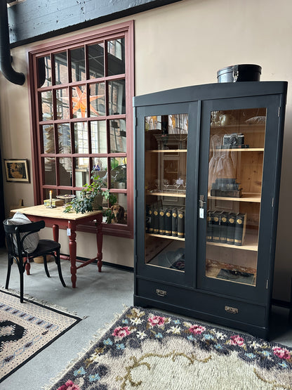 Ett gammalt, vackert vitrinskåp med rundad överkant.Skåpet har två glasdörrar. 