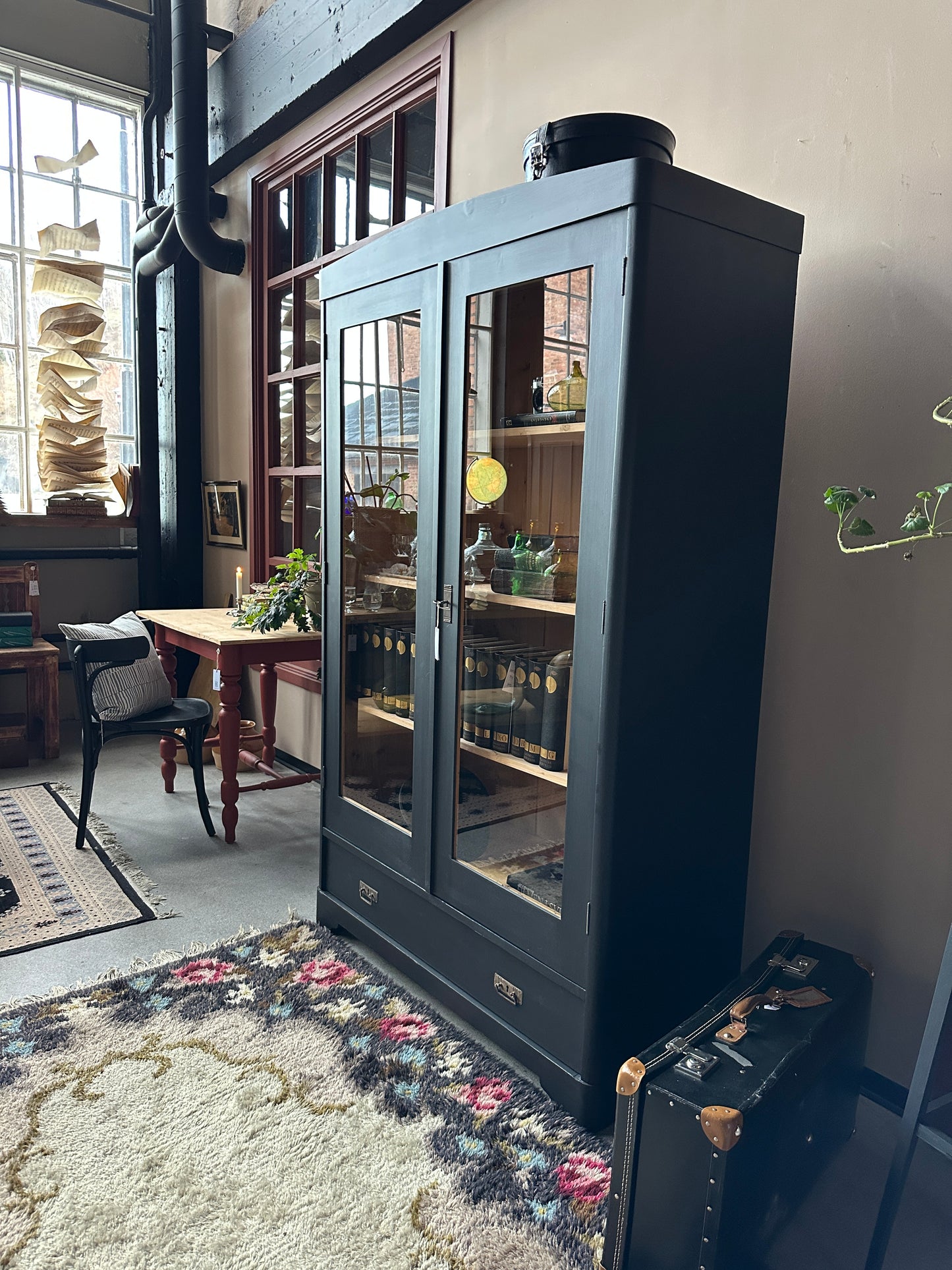 Ett gammalt, vackert vitrinskåp med rundad överkant.Skåpet har två glasdörrar. 